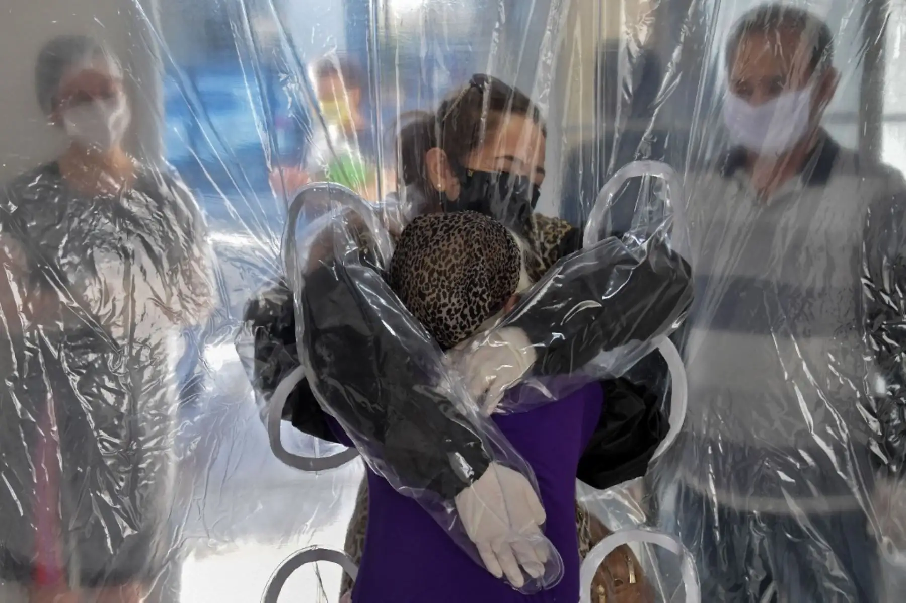 Elisabete Nagata abraza a su cuñada Luiza Nagata, de 76 años, a través de una cortina de plástico transparente en un hogar de ancianos en Sao Paulo, Brasil. Foto: AFP