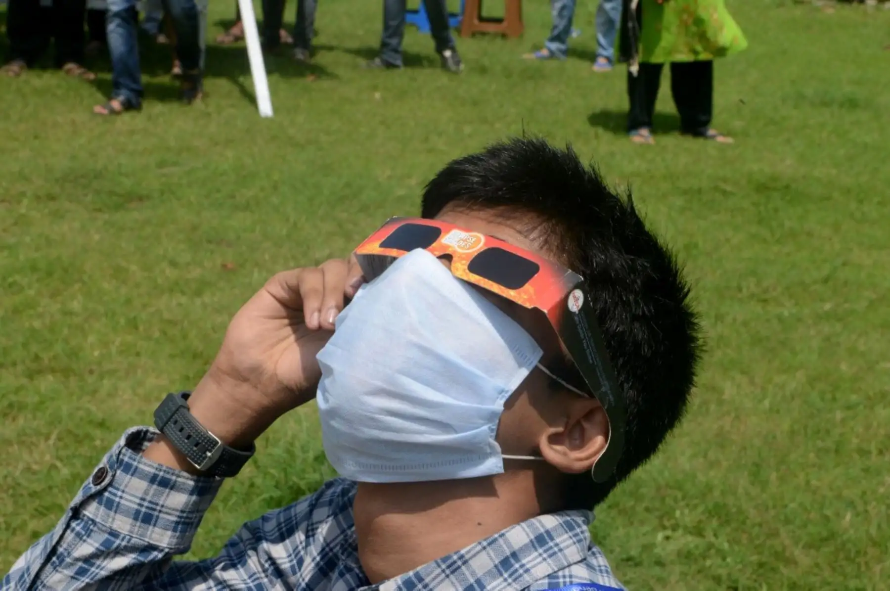 Un joven utiliza un par de gafas para ver el eclipse solar anular en Siliguri, en la India. Foto: AFP