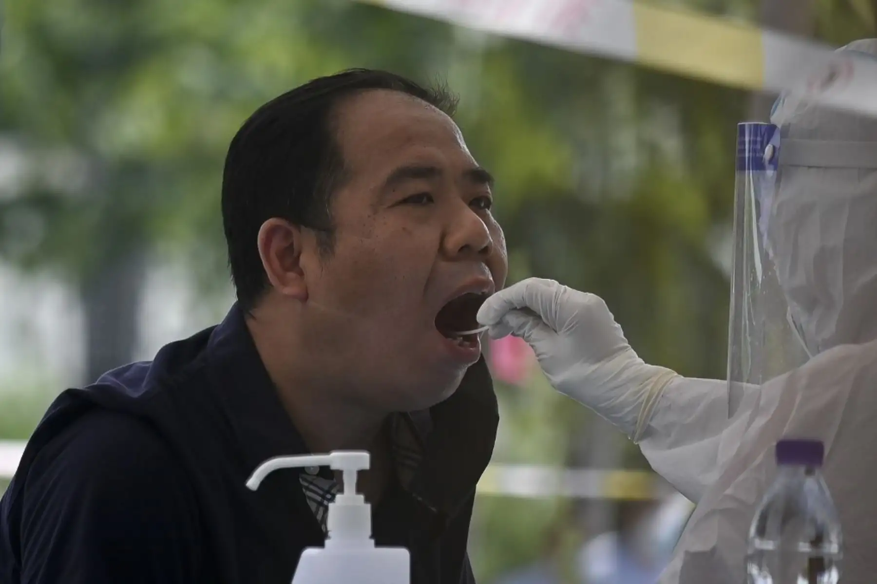 Un trabajador de la salud que usa un traje protector toma una prueba de hisopo de un hombre para detectar el coronavirus covid-19 en un sitio de prueba en Pekín, China. Foto: AFP