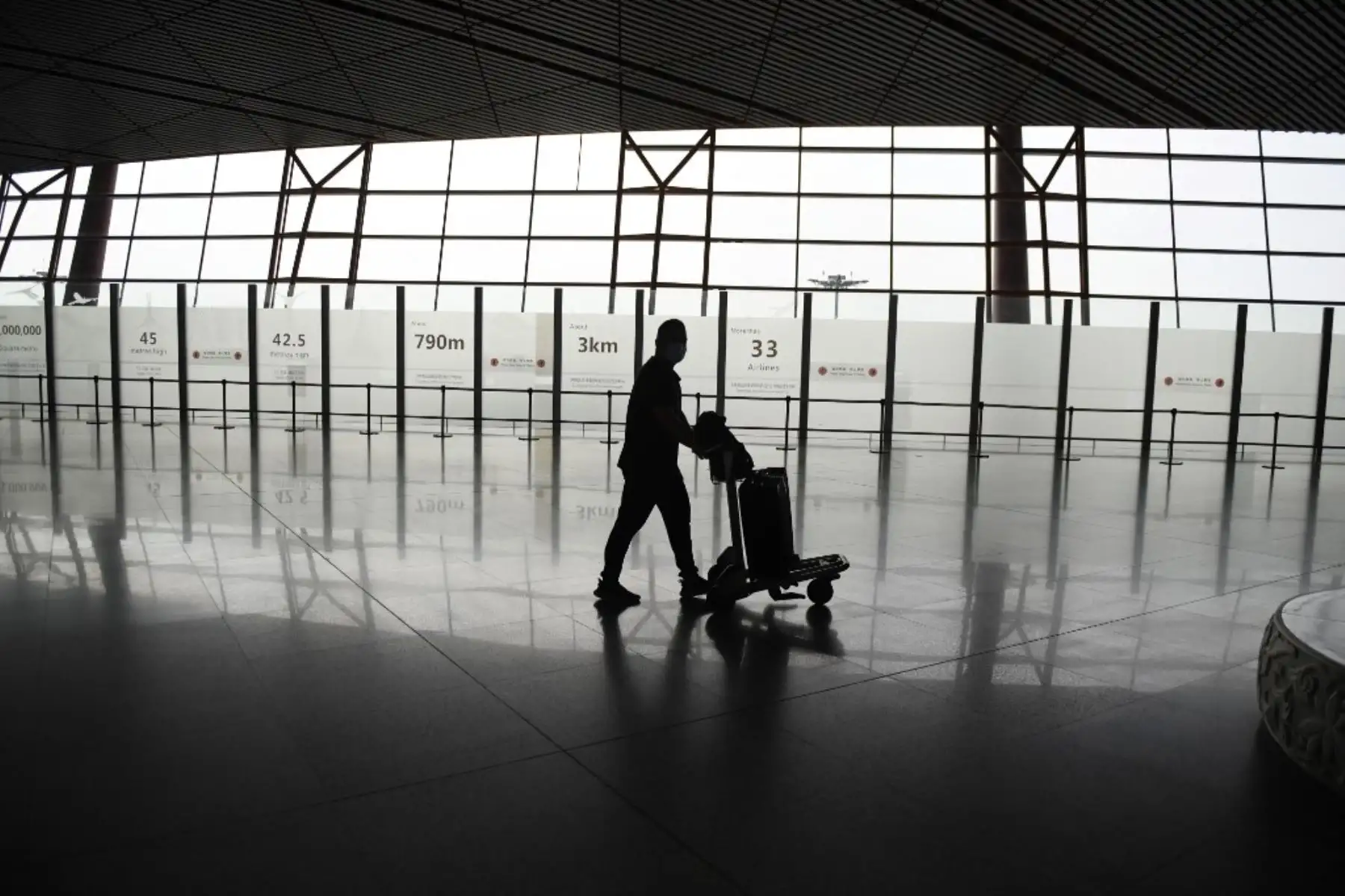 Un pasajero solitario camina por el aeropuerto de Pekín. Foto: AFP