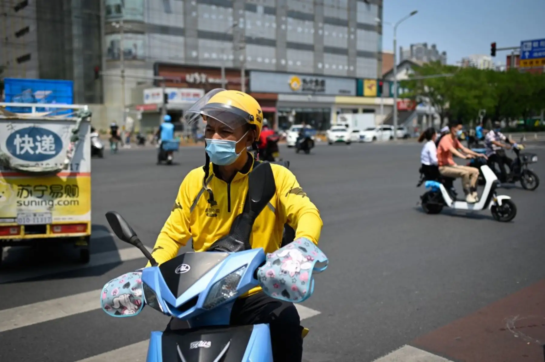 Un conductor de reparto de alimentos con una máscara facial monta una bicicleta eléctrica en una calle de Pekín. Foto: AFP
