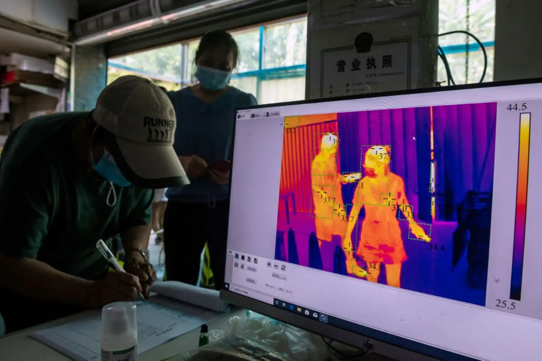 Los clientes se registran y se les verifica la temperatura mediante imágenes térmicas antes de ingresar a un mercado en Pekín. Foto: AFP
