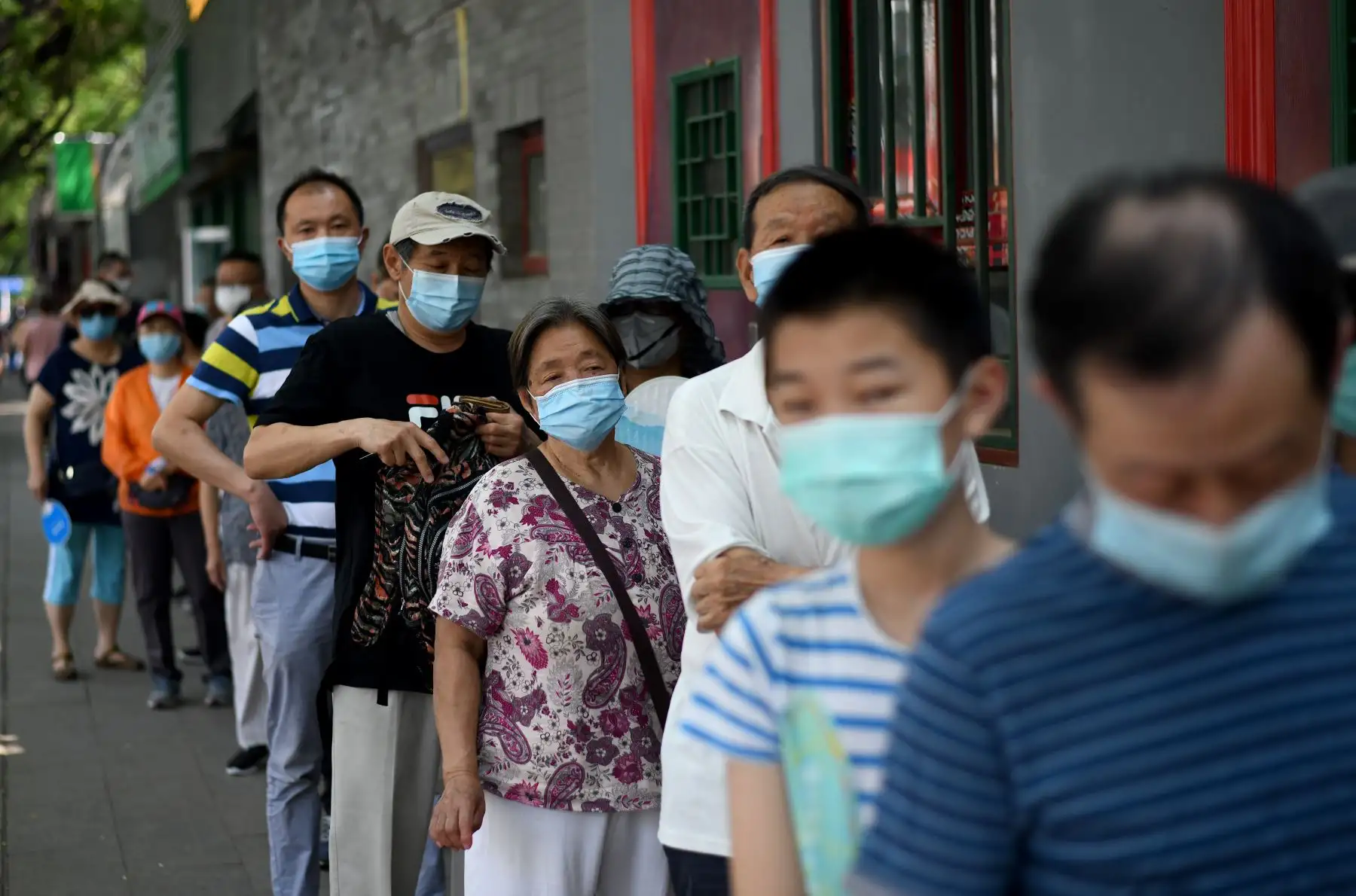 Las personas que usan mascarillas hacen cola para tomar una prueba de hisopo durante las pruebas masivas para el coronavirus covid-19 en Pekín. Foto: AFP