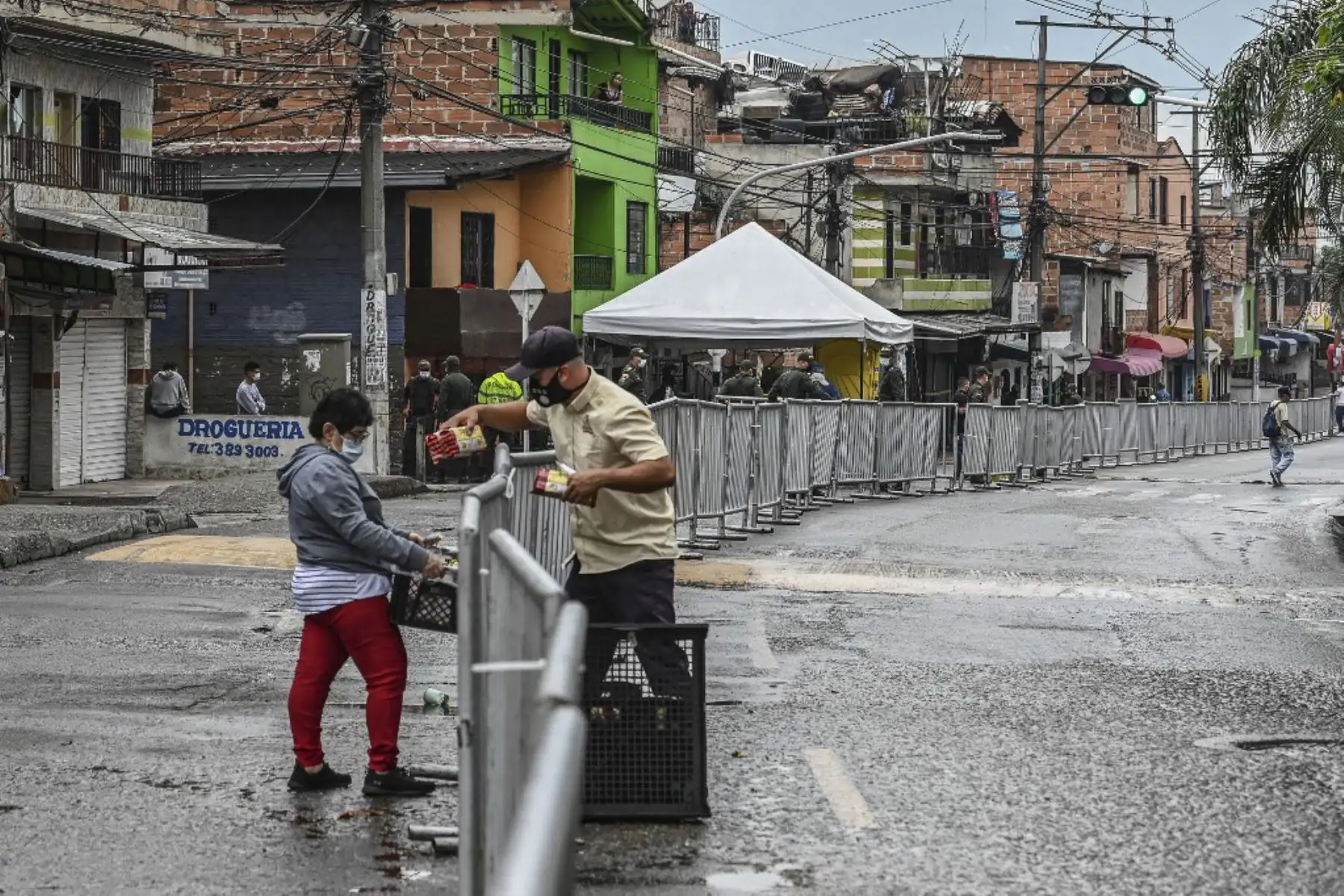 Un hombre entrega pan a una mujer, ambos con mascarillas como medida preventiva contra la propagación del covid - 19 en el barrio de Santa Cruz en Medellín.
Foto: AFP