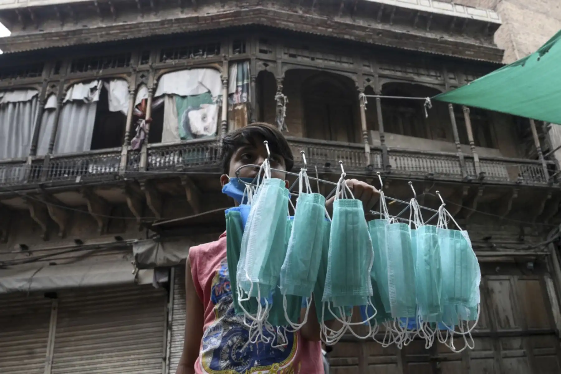 Un joven vendedor vende máscaras faciales en una calle cerca de un área restringida sellada por las autoridades en Lahore el 25 de junio de 2020, ya que los casos de coronavirus COVID-19 continúan aumentando. Foto: AFP