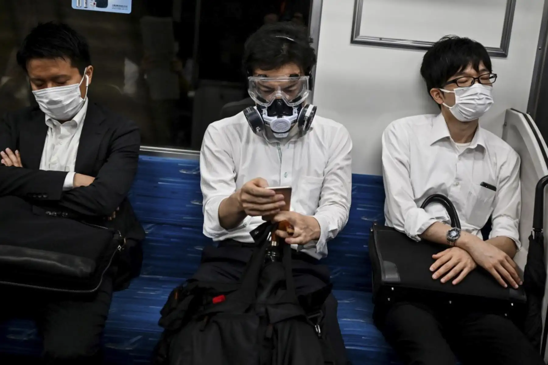 Un hombre que usa un respirador y gafas se encuentra entre los pasajeros en un tren en Tokio. Foto:AFP