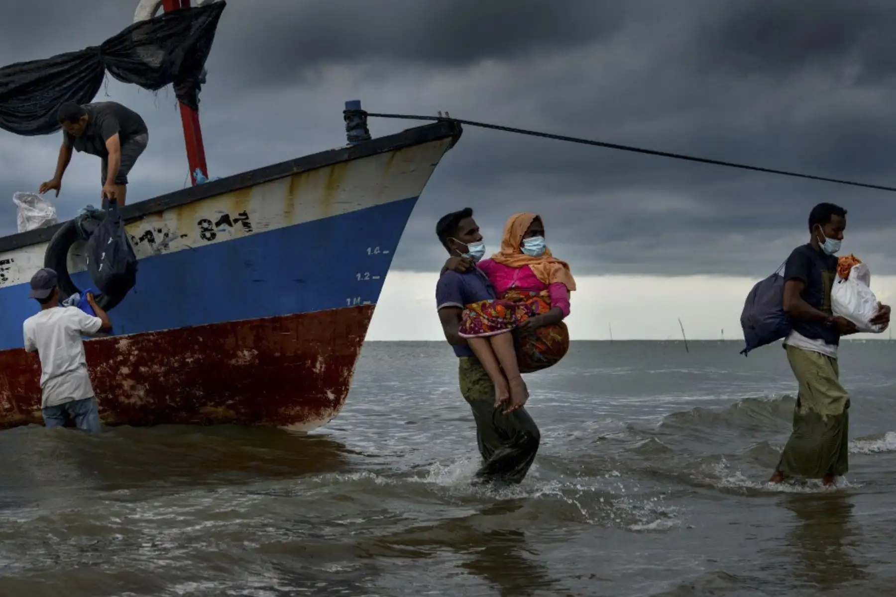 Los pescadores de Acehnesse ayudan a evacuar a una mujer rohingya de Myanmar a las costas de la aldea de Lancok, en la regencia de Aceh del norte de Indonesia. Foto:AFP