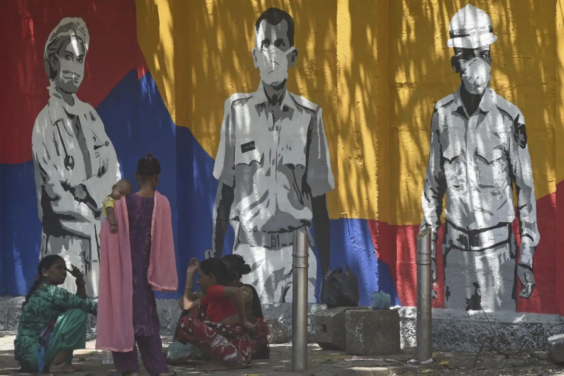 Un grupo de mujeres se sienta cerca de un mural pintado para agradecer a los trabajadores de primera línea que luchan contra la propagación del coronavirus covid-19, en Mumbai.Foto:AFP