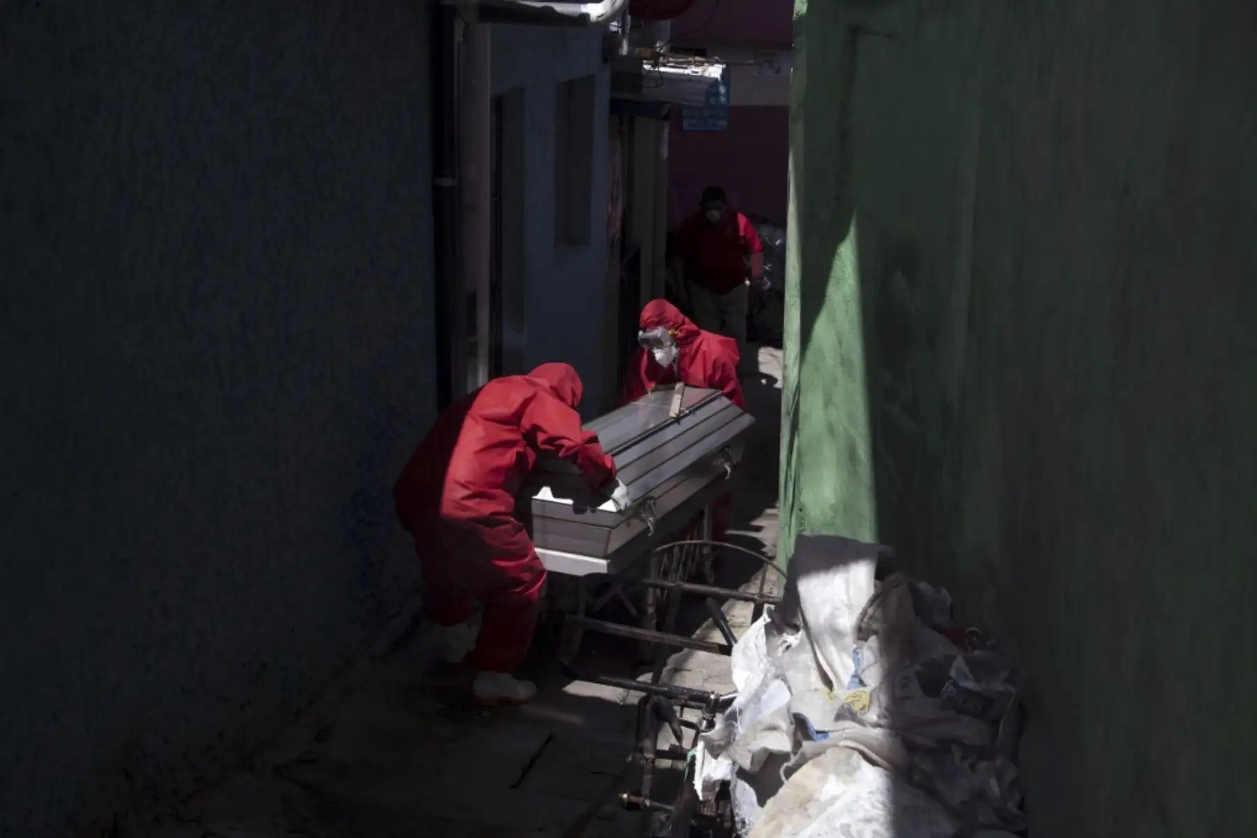 Trabajadores funerarios vestidos con trajes de bioseguridad llevan el cuerpo de un hombre de 75 años que murió, supuestamente víctima de covid-19 en San Salvador.Foto:AFP