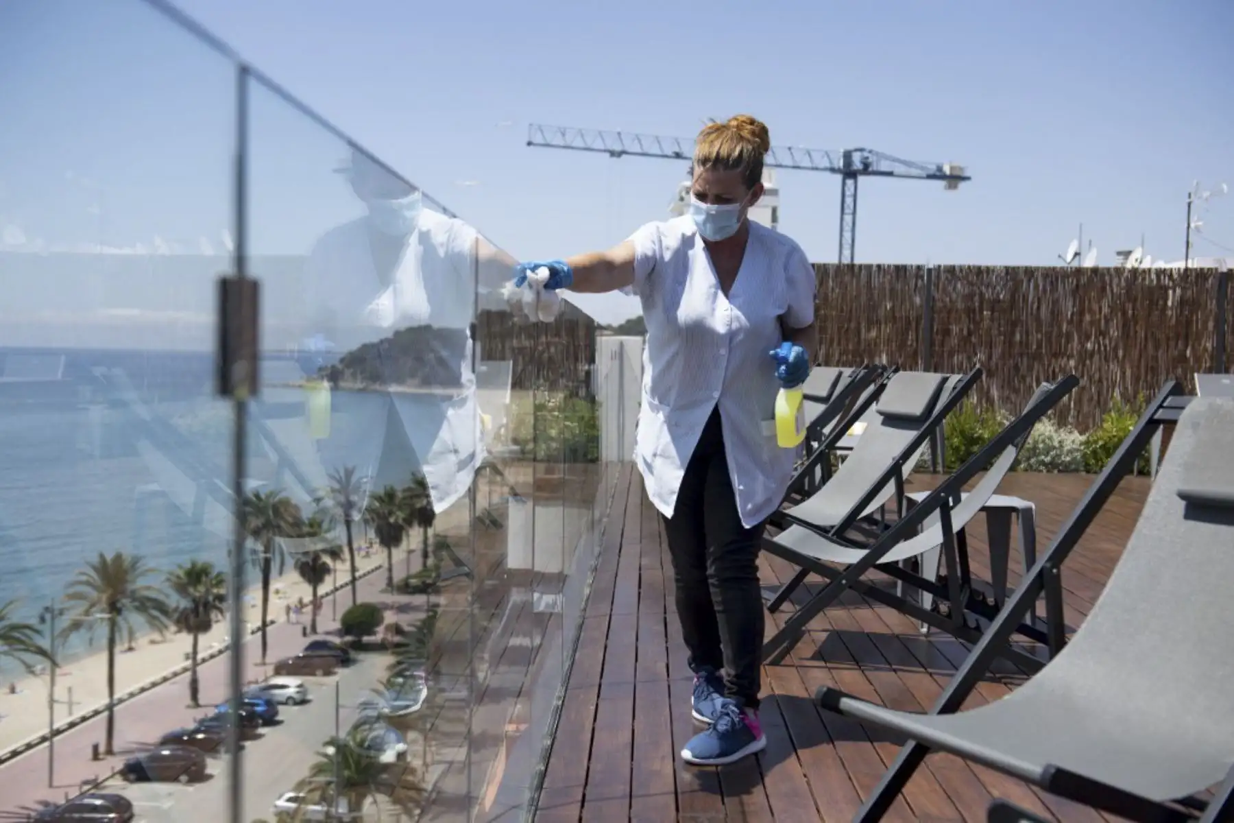 Un empleado del hotel limpia una barrera de vidrio en una terraza con vista a una playa en Lloret de Mar, a medida que las playas vuelven a abrir en España después de un cierre nacional para detener la propagación del nuevo coronavirus.Foto:AFP