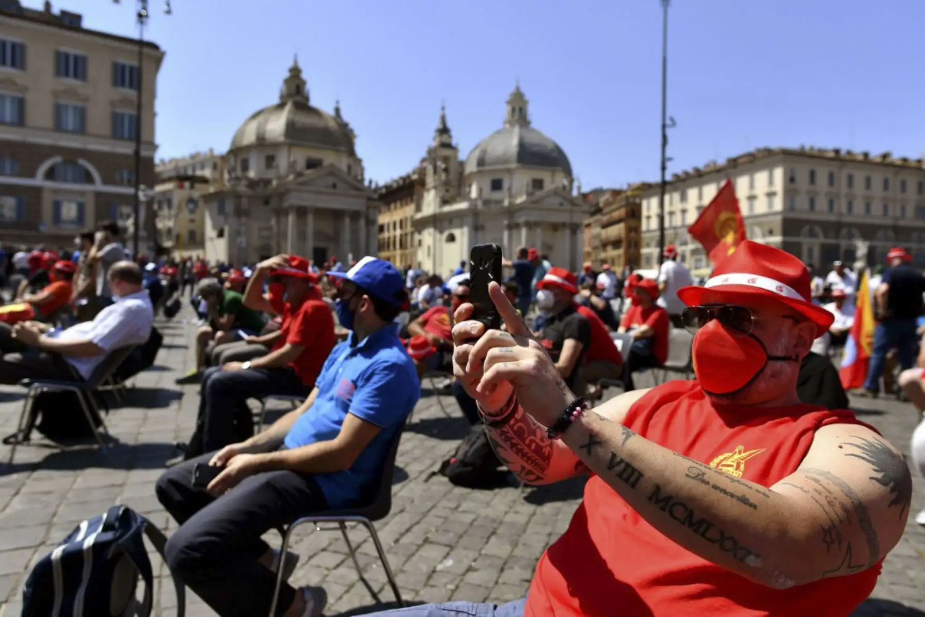 Las personas usan máscaras protectoras y se sientan respetando las distancias de seguridad mientras participan en una manifestación en Italia. Foto:AFP