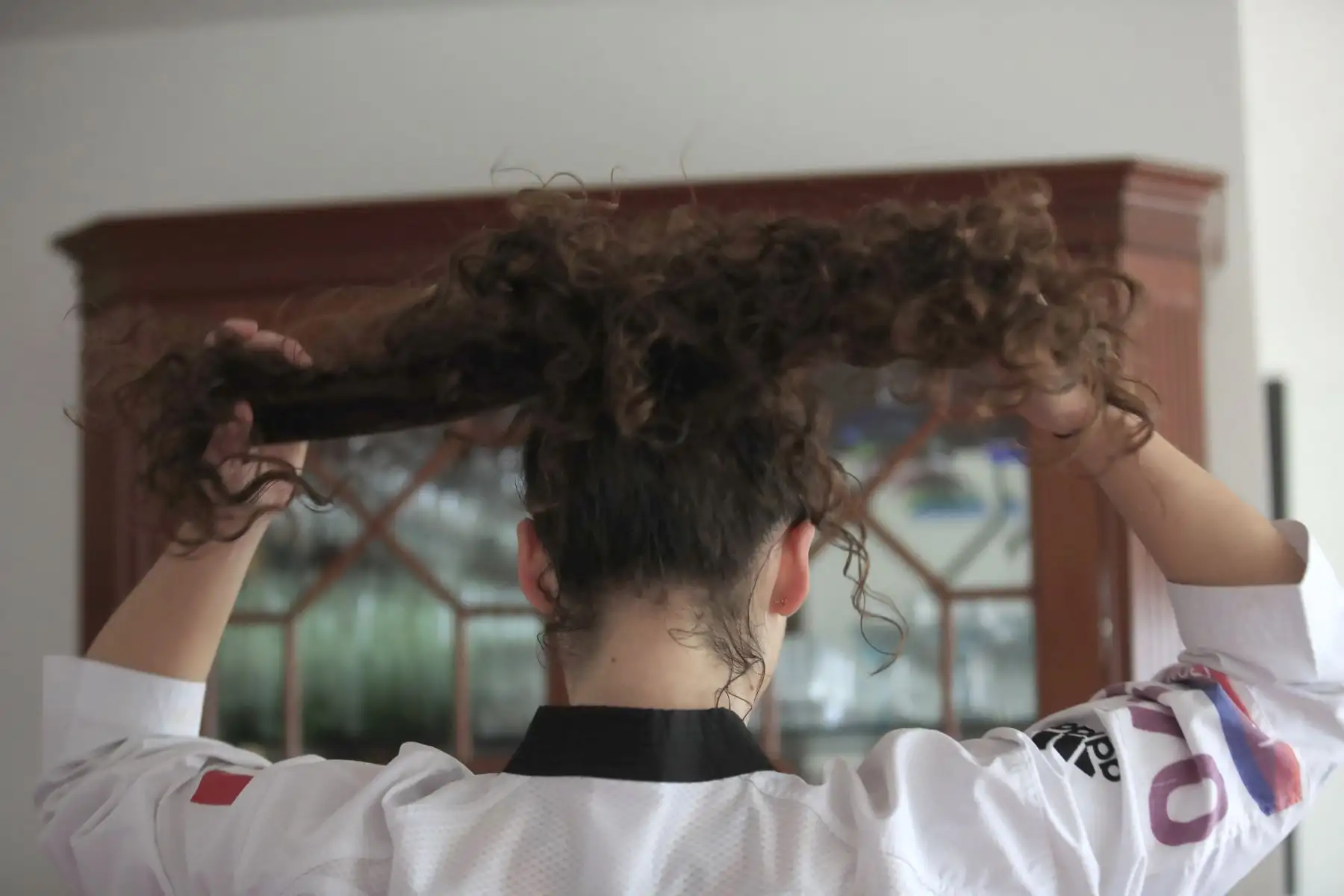 Aittana Moya, deportista practicante de Taekwondo amarra su cabello para poder realizar sus entrenamientos de alta competencia en la sala de su departamento. Debido a la cuarentena impuesta por el Estado para evitar contagios de covid-19 muchos deportistas han adecuado su viviendas como centro de preparación para no perder el ritmo competitivo.
Foto: ANDINA / Juan Carlos Guzmán Negrini