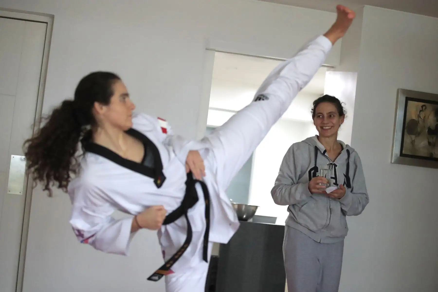 Aittana Moya, deportista practicante de Taekwondo realiza sus entrenamientos de alta competencia en la sala de su departamento bajo la atenta mirada de su madre, Rommy Hubner, que le trae un vaso con agua de la cocina. Debido a la cuarentena impuesta por el Estado para evitar contagios de covid-19 muchos deportistas han adecuado su viviendas como centro de preparación para no perder el ritmo competitivo.

Foto: ANDINA / Juan Carlos Guzmán Negrini