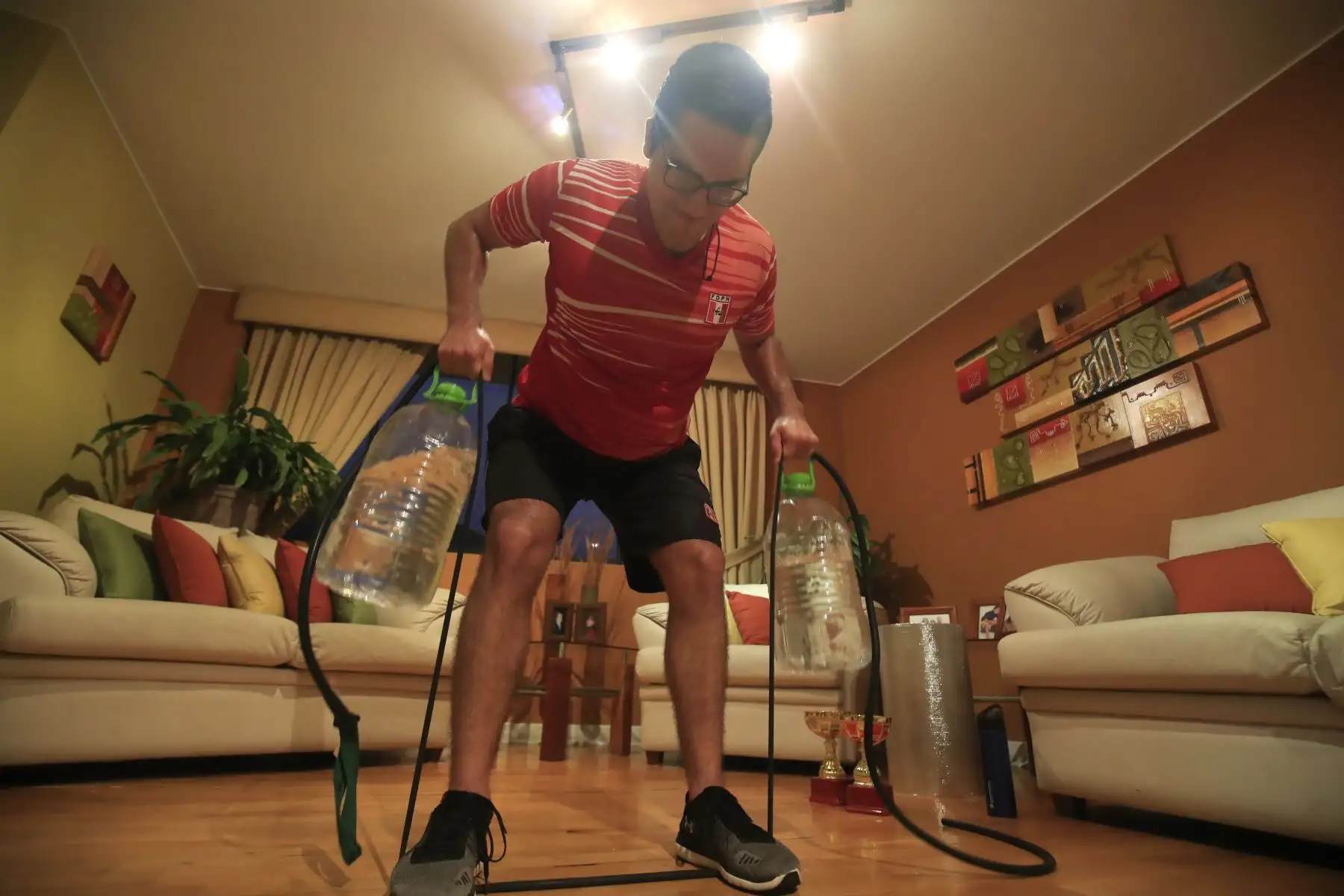 Rodrigo Ramírez deportista modalidad natación en aguas abiertas utiliza dos botellones llenos de agua y una banda elástica de resistencia como parte de su entrenamiento. Debido a la cuarentena impuesta por el Estado para evitar contagios de covid-19 muchos deportistas han adaptado sus viviendas como centro de preparación para no perder el ritmo competitivo.

Foto: ANDINA / Juan Carlos Guzmán Negrini