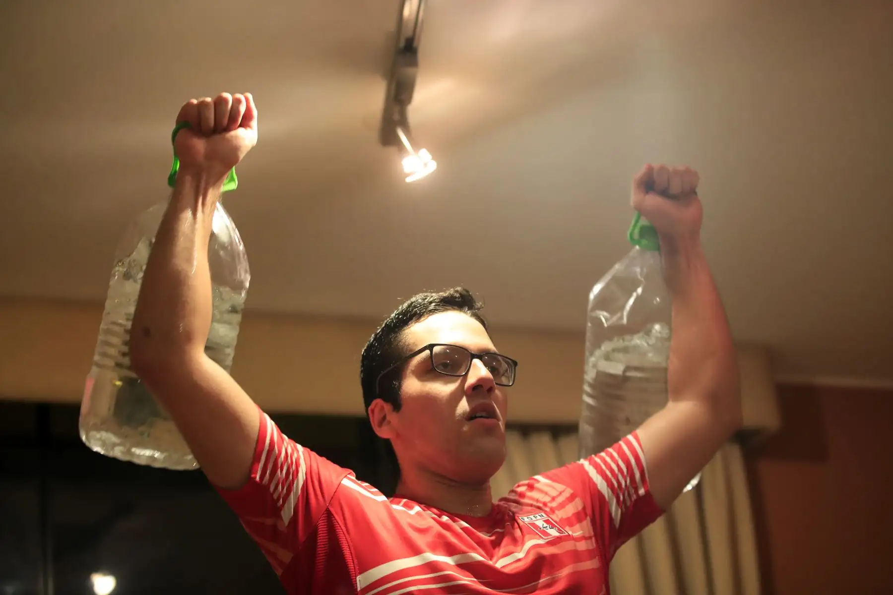 Rodrigo Ramírez deportista modalidad natación en aguas abiertas se ejercita con dos botellones llenos de agua como pesas. Debido a la cuarentena impuesta por el Estado para evitar contagios de covid-19 muchos deportistas han adaptado sus viviendas como centro de preparación para no perder el ritmo competitivo.

Foto: ANDINA / Juan Carlos Guzmán Negrini