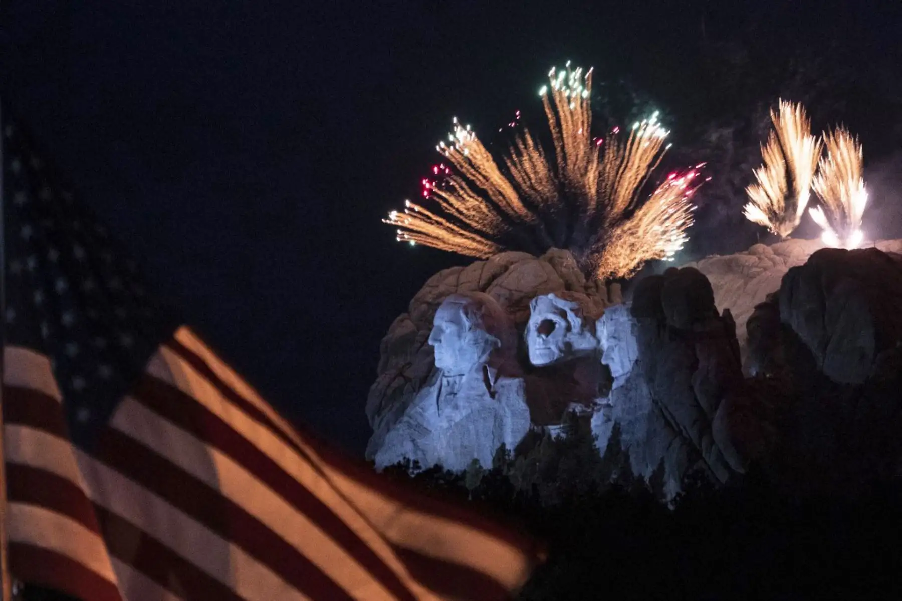 Una bandera de los Estados Unidos ondea mientras los fuegos artificiales explotan sobre el Monumento Nacional del Monte Rushmore durante un evento del Día de la Independencia al que asistió el presidente de los Estados Unidos en Keystone, Dakota del Sur. Foto: AFP