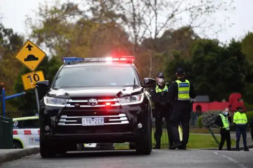 Agentes de la Policía de Victoria vigilan en las afueras de una torre de viviendas públicas en Racecourse Road en Melbourne, Australia, después de que se decretara el cierre inmediato de nueve torres en Flemington y North Melbourne tras registrarse un brote de coronavirus. Foto: EFE