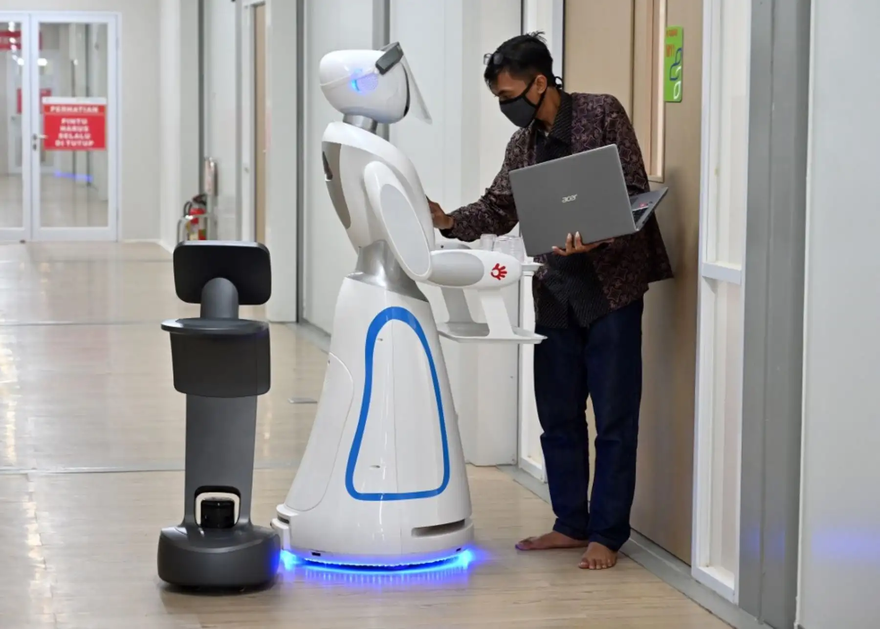 Un técnico indonesio examina a 2 robots conocidos como Amy y Temi durante una simulación para ayudar a los médicos a atender pacientes con coronavirus COVID-19 en el hospital Pertamina Jaya en Yakarta. Foto: AFP