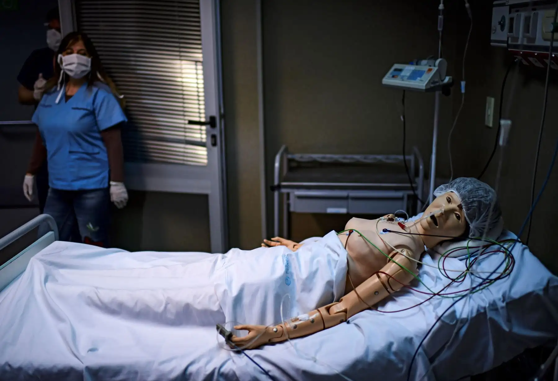La doctora Norma Raul mira un robot con el que practica asistencia médica para pacientes con COVID-19, en el Centro de Entrenamiento de Simulación Clínica del hospital El Cruce en Buenos Aires, Argentina. Foto: AFP