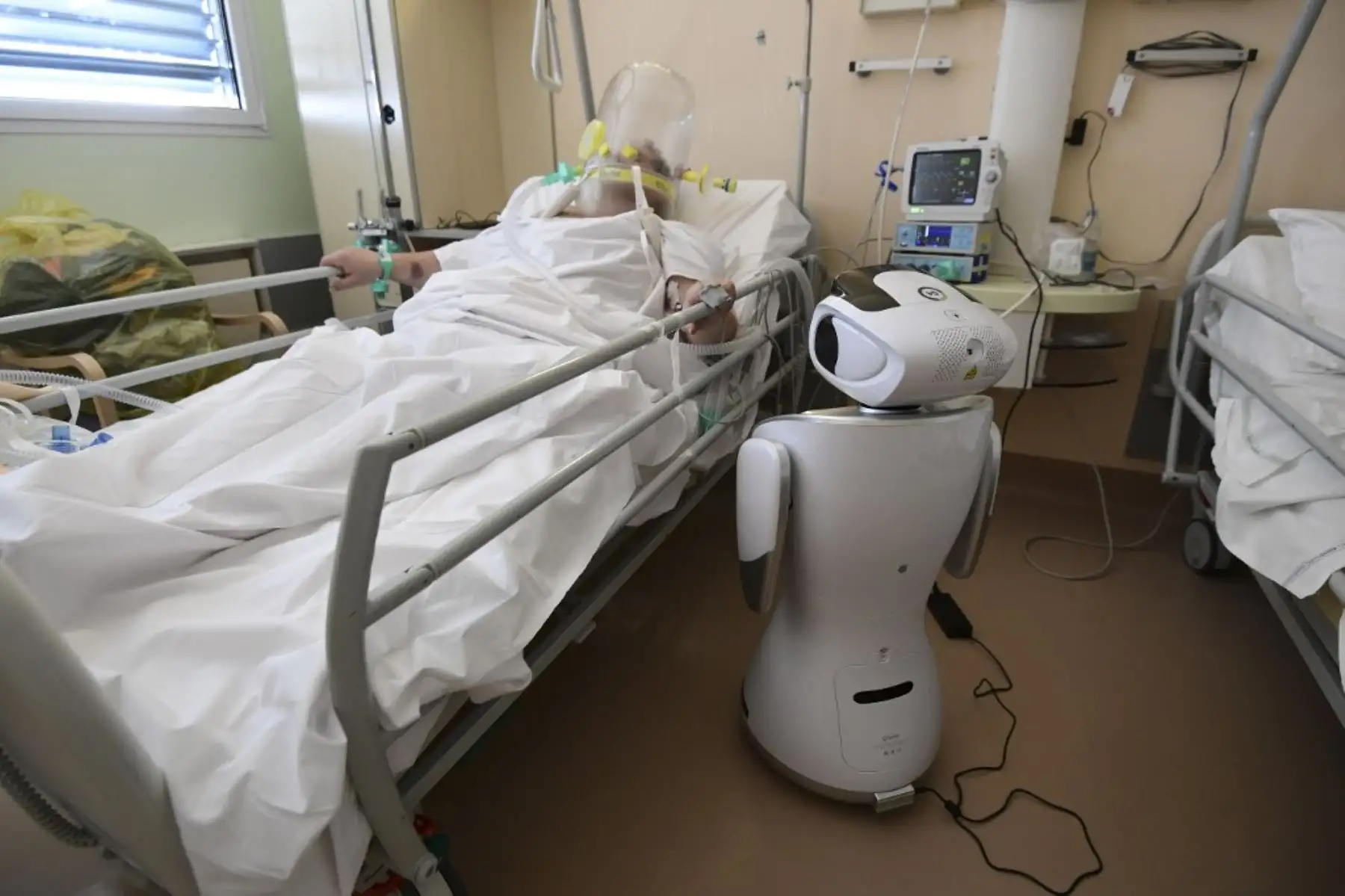 Uno de los seis robots del hospital Circolo di Varese se encuentran cerca de un paciente para ayudar al personal de atención médica del departamento de Medicina de Alta Intensidad, en Italia. Foto: AFP