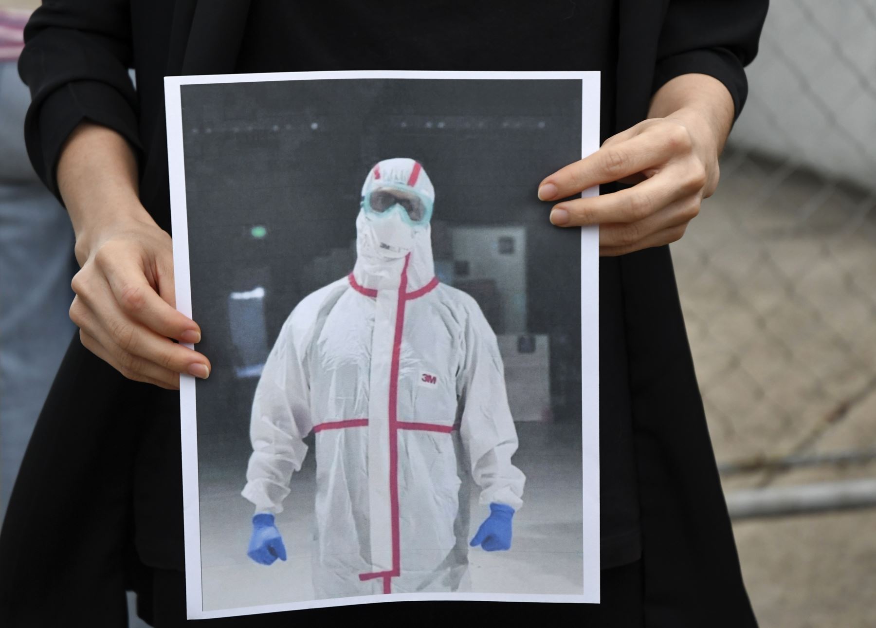 Un colega del doctor Oscar Hernández, quien murió de covid-19, sostiene un retrato de él en un traje de protección en el Parque Industrial en la Ciudad de Guatemala. Foto: AFP