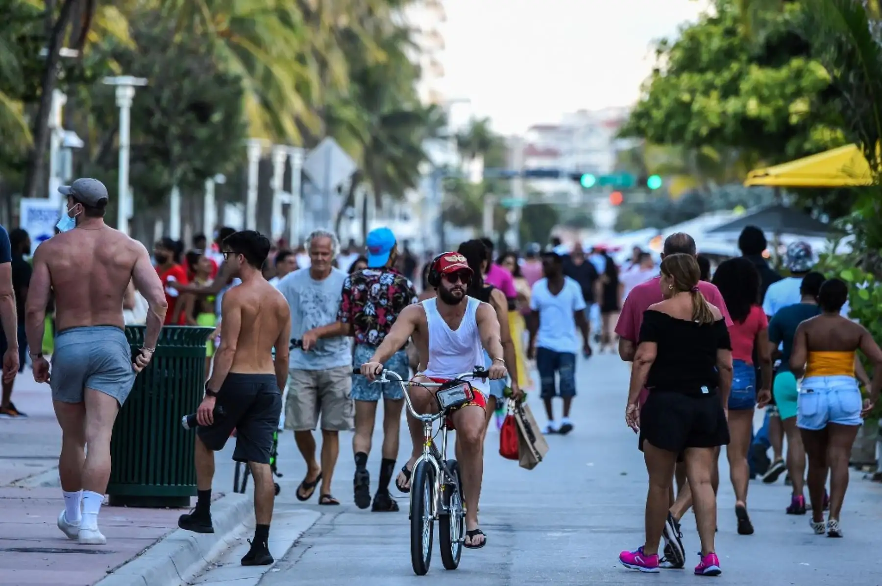 Un hombre monta una bicicleta mientras la gente camina en Ocean Drive en Miami Beach, Florida. Foto: AFP