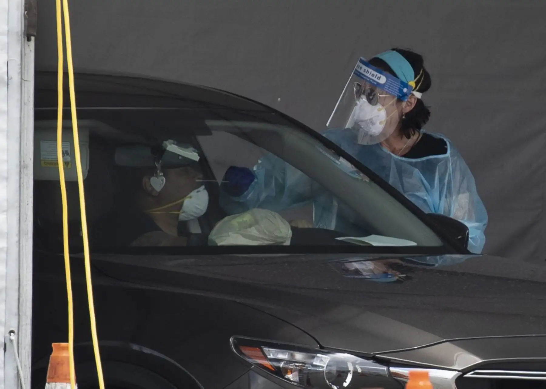 Un trabajador de salud examina a una persona por covid-19 en el sitio de prueba covid ubicado en el estacionamiento del Hard Rock Stadium en Miami. Foto: AFP