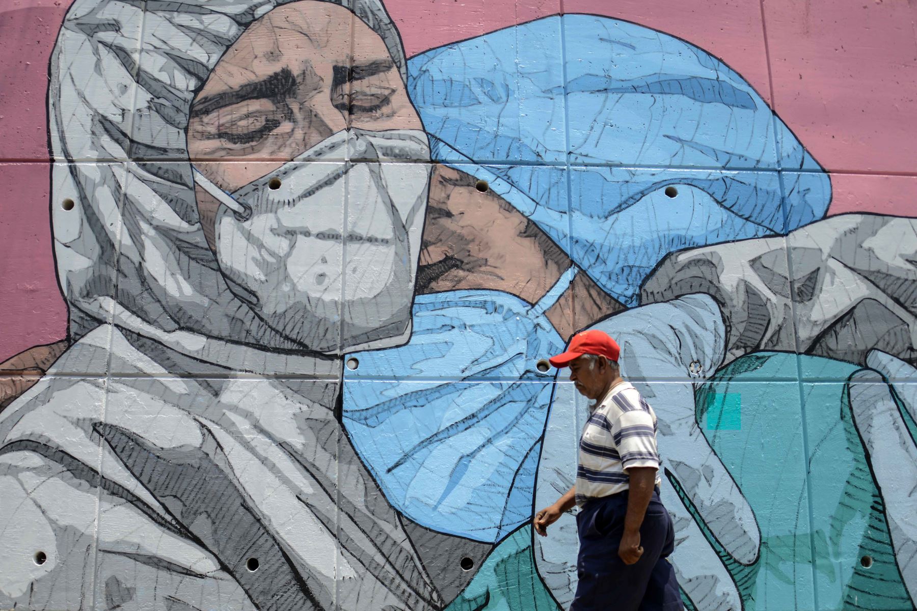 Ciudadano mexicano pasa junto a un mural relacionado con el coronavirus, en Acapulco, Estado de Guerrero, México, en medio de la pandemia del covid-19. Foto: AFP
