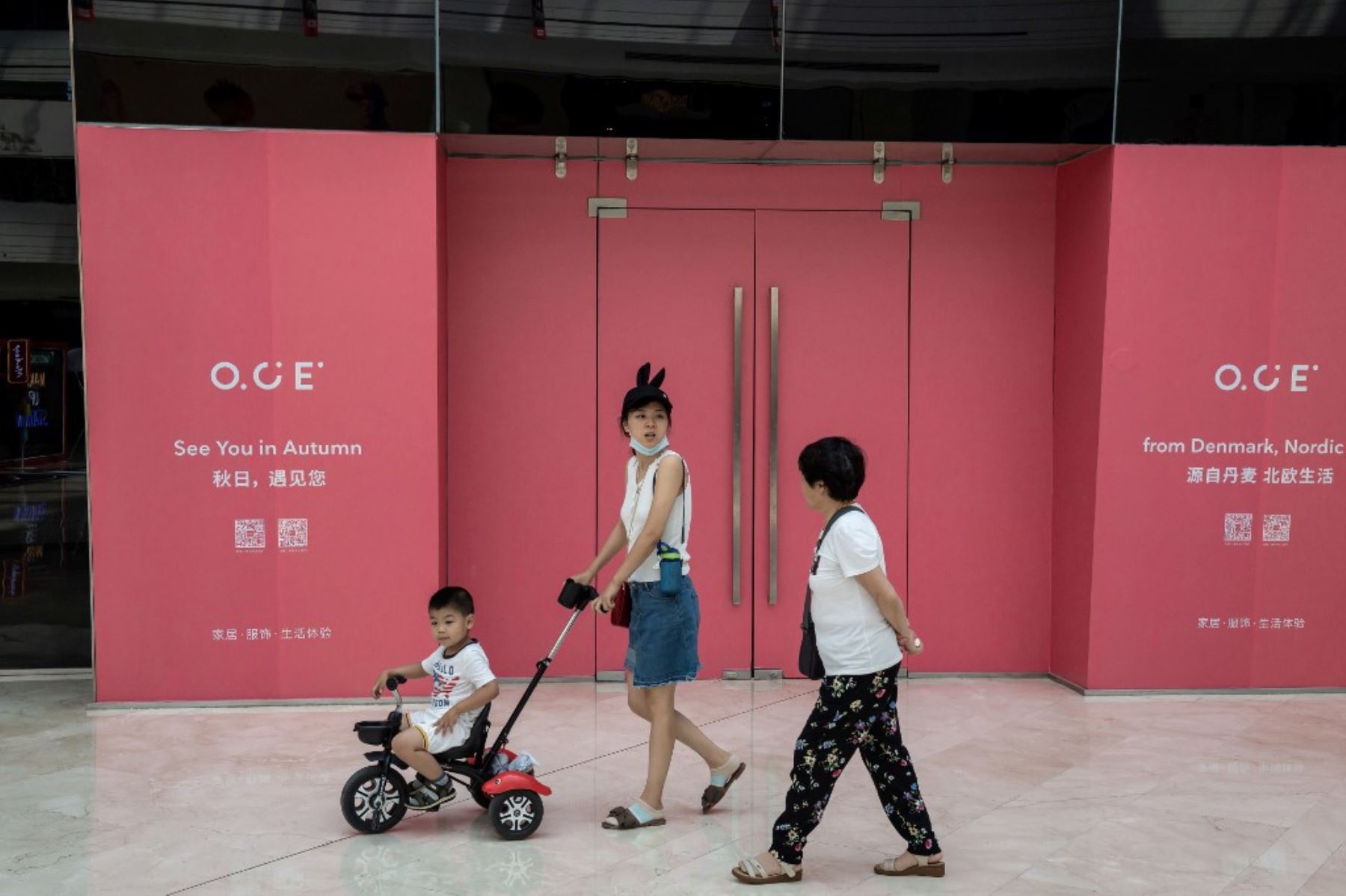 La gente pasa frente a una tienda cerrada que abrirá en otoño, dentro de un centro comercial en Beijing. Foto: AFP