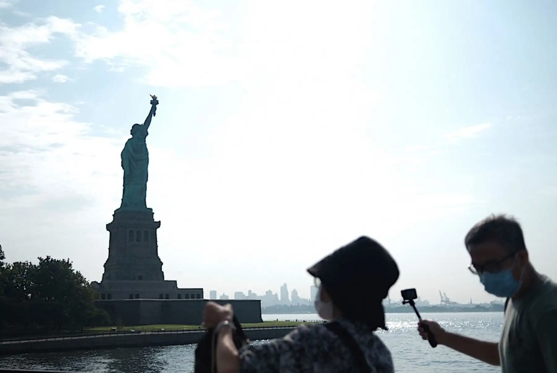 Los turistas toman fotos de la Isla de la Libertad reabierta con la Estatua de la Libertad frente al horizonte del Bajo Manhattan. Foto: AFP