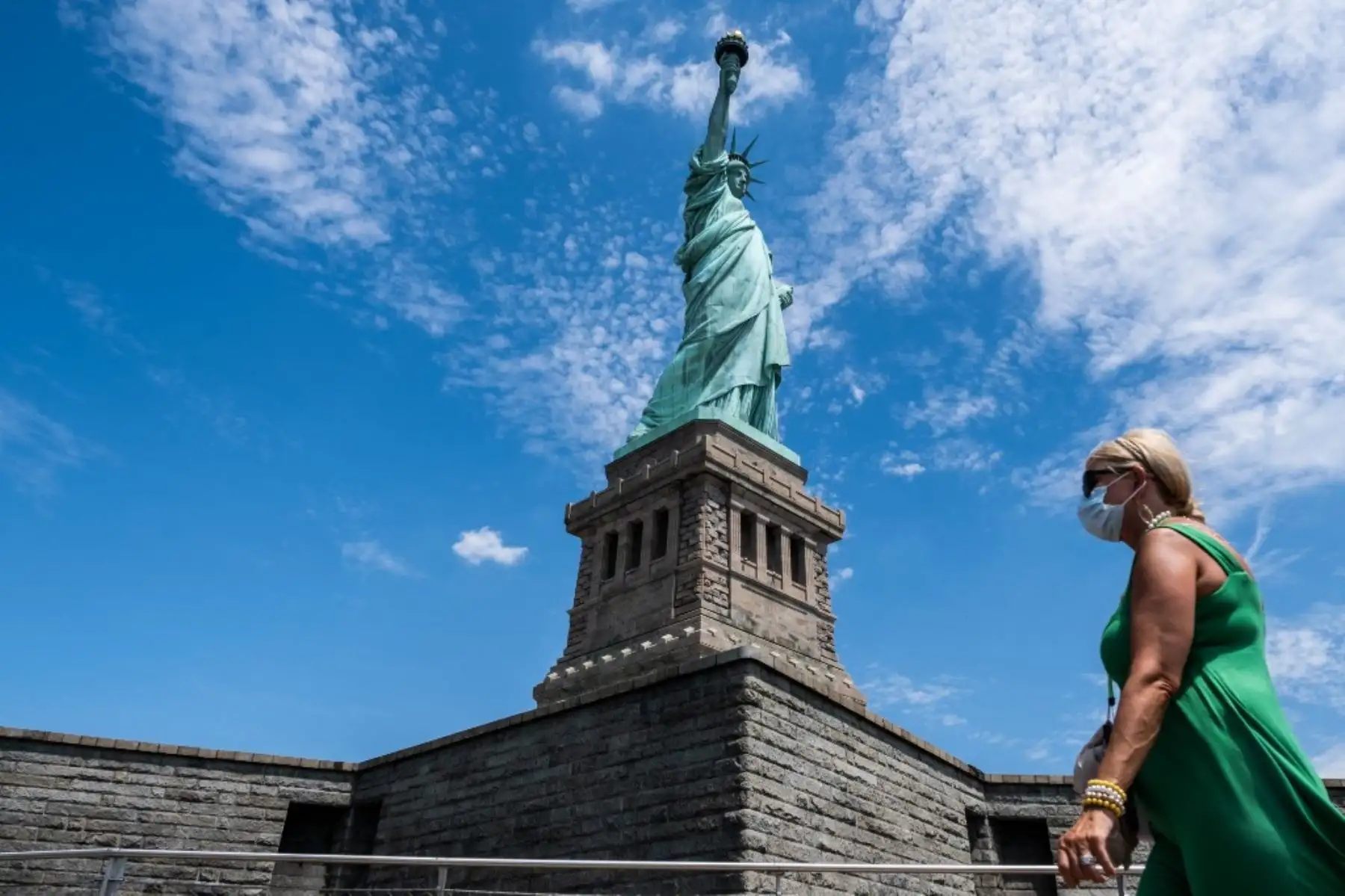 Un visitante con una máscara protectora pasa junto a la Estatua de la Libertad. Foto: AFP