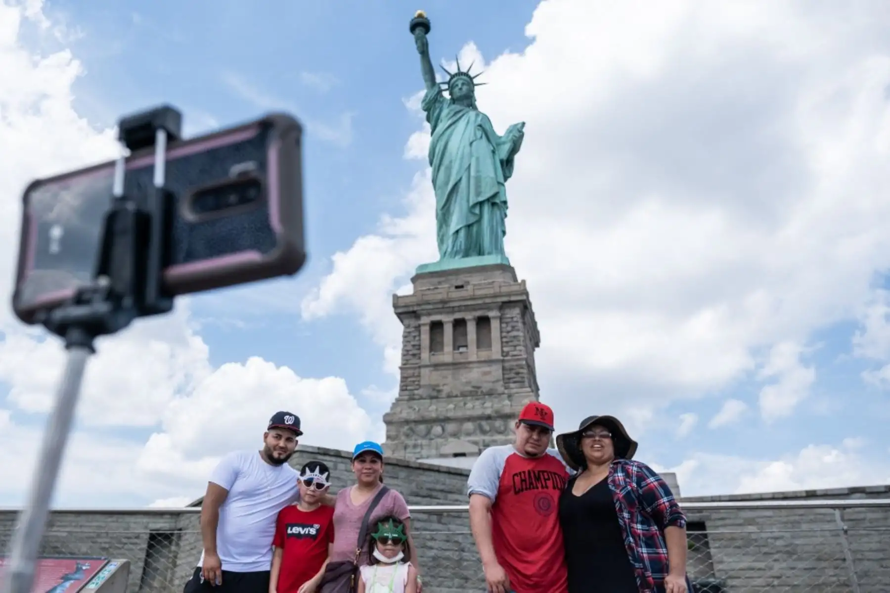 Los visitantes posan para una foto frente a la Estatua de la Libertad en la ciudad de Nueva York. Foto: AFP