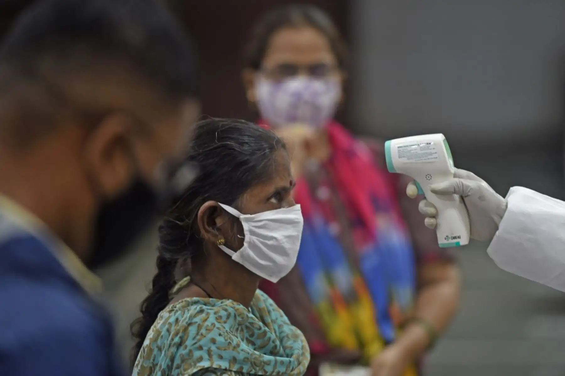 Un voluntario médico toma la lectura de temperatura de una mujer en Mumbai. Foto: AFP