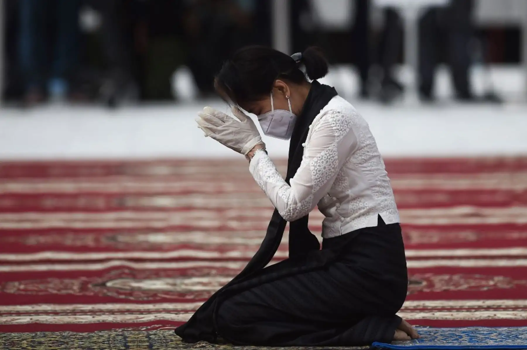 La consejera estatal y ministra de Asuntos Exteriores de Myanmar, Aung San Suu Kyi, usa guantes y una máscara facial mientras reza por su difunto padre. Foto: AFP