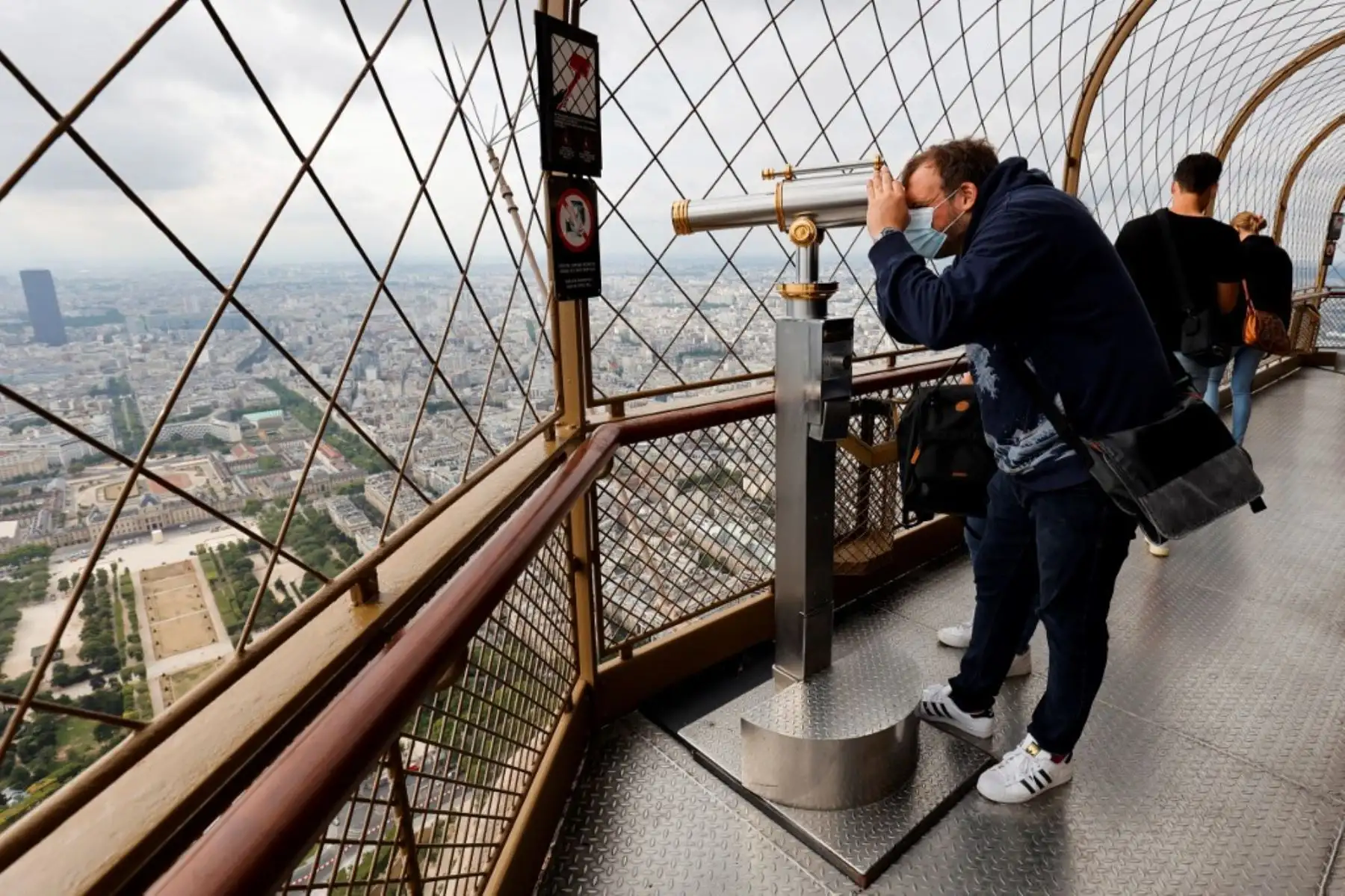 Un hombre mira a través de un monocular en la Torre Eiffel durante su reapertura. Foto: AFP