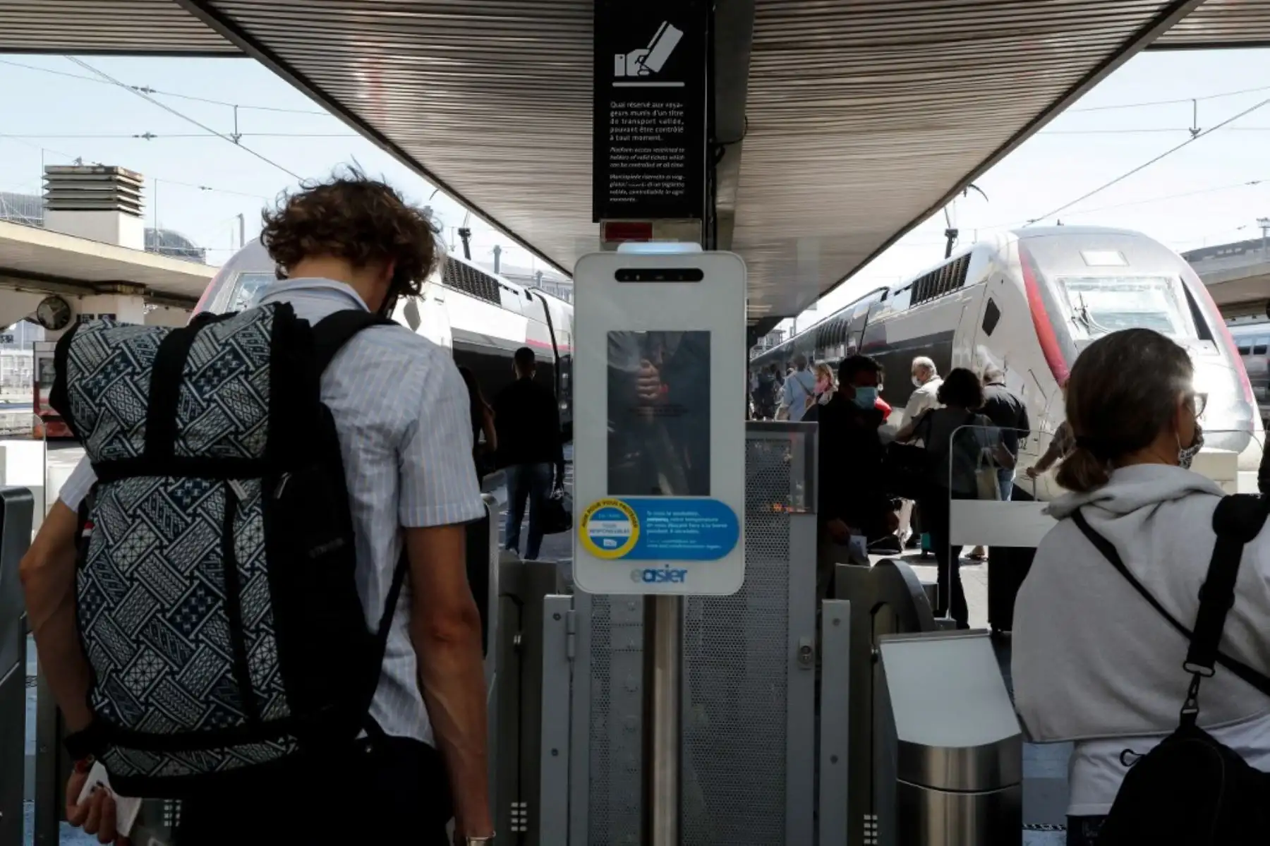 Los viajeros deben controlar su temperatura en la puerta de seguridad, antes de abordar un tren de alta velocidad TGV en la estación de tren Gare de Lyon en París. Foto: AFP