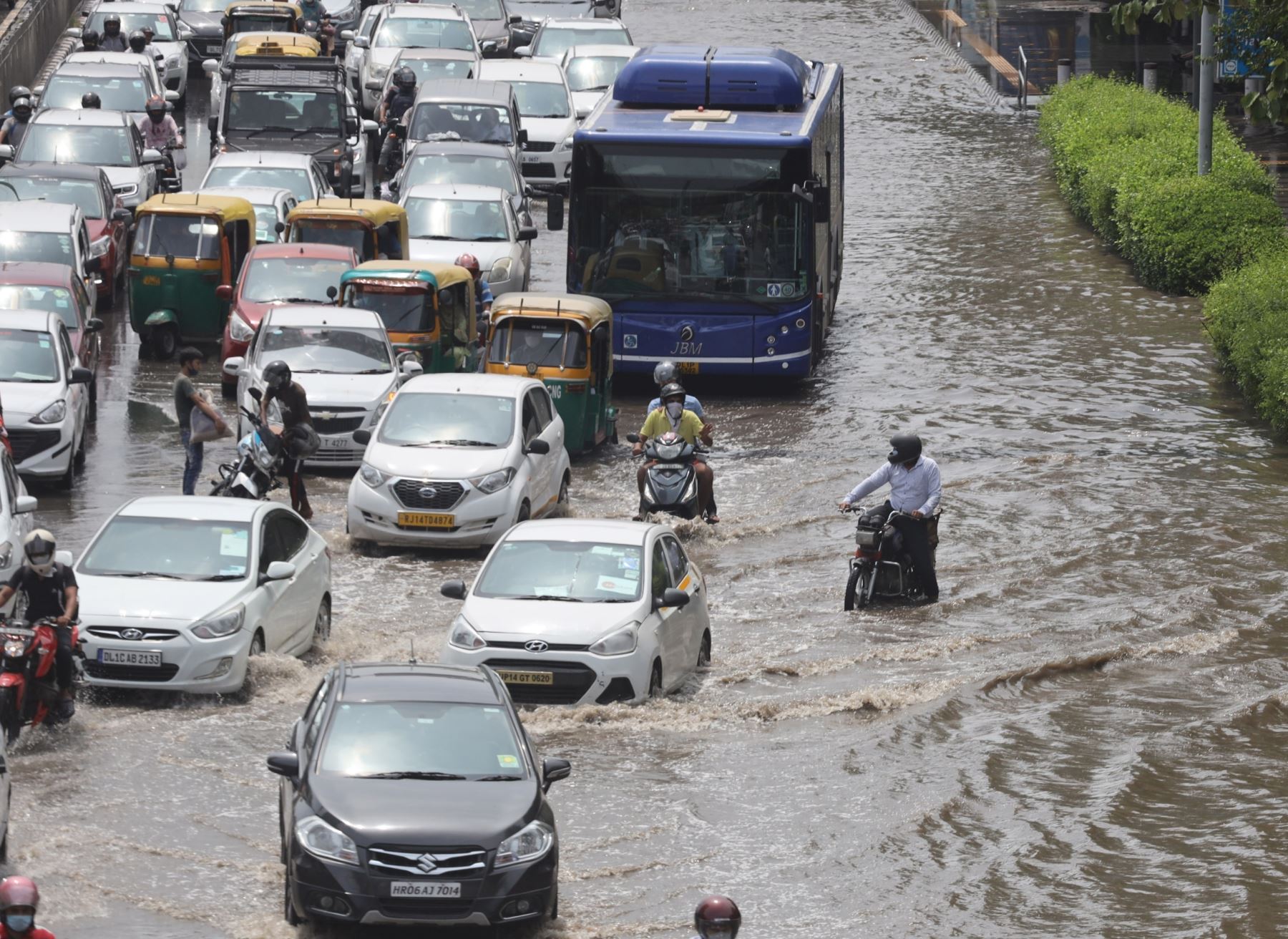 Varias personas tratan de avanzar en una carretera anegada de agua debido a las fuertes lluvias ocasionadas en Nueva Delhi, en la India. Foto: EFE