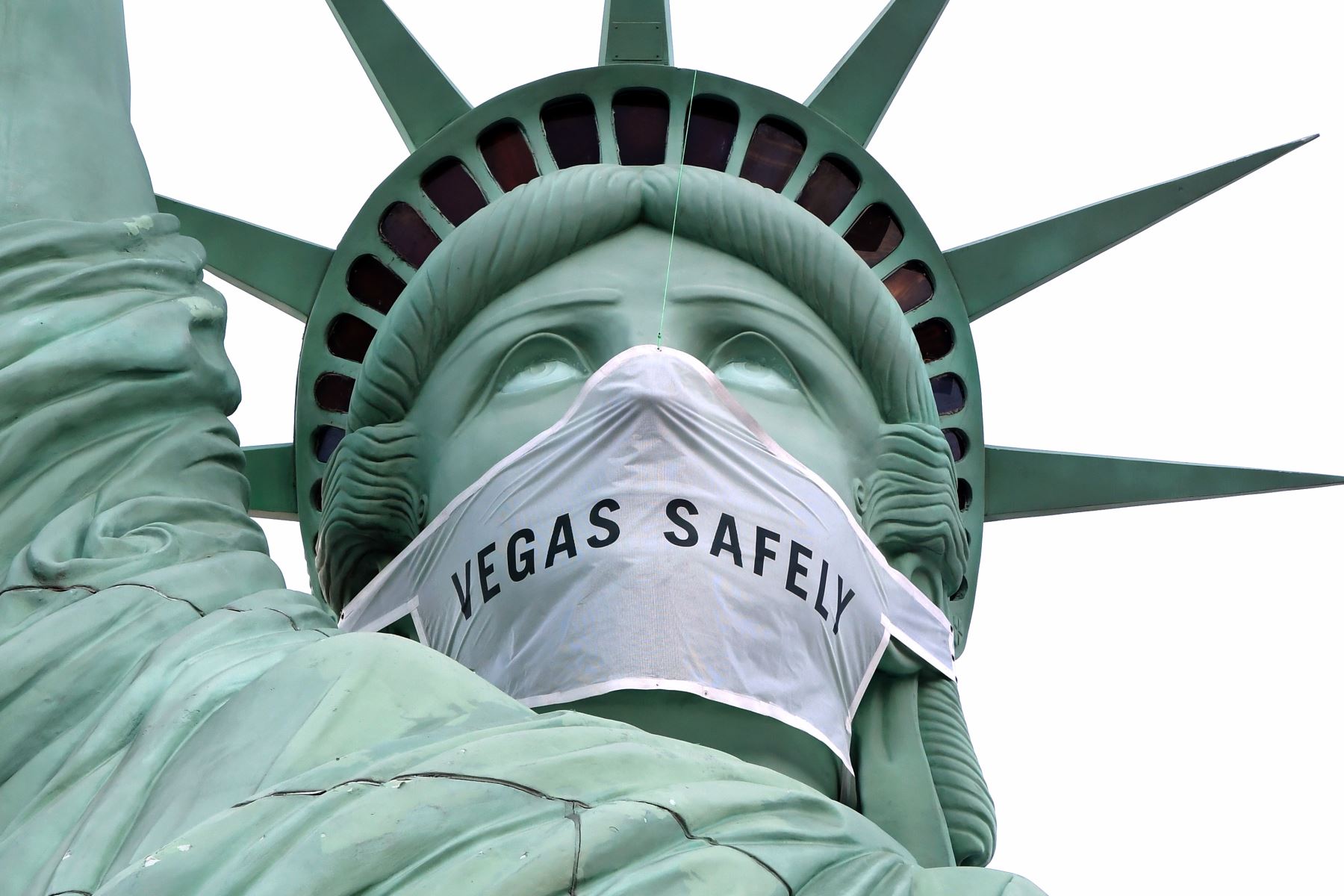 Una máscara de gran tamaño, que dice "Las Vegas, de manera segura", cubre la cara de la réplica de La Estatua de la Libertad en el New York-New York Hotel & Casino en Las Vegas, Nevada. Foto: AFP