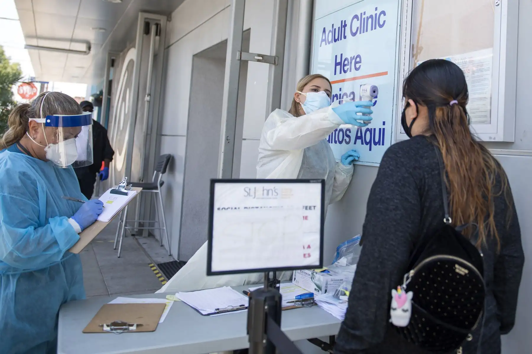 Una trabajadora de salud toma la temperatura de un paciente antes de enviarlo a una tienda de campaña para que lo examinen en un sitio de prueba de COVID-19 en el Centro de Niños y Familias de St. John