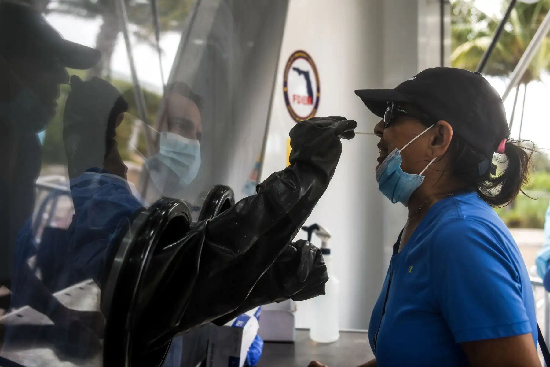 Un médico limpia la nariz de un ciudadana a través de un panel del camión móvil de pruebas Covid-19, en Miami. Foto: AFP