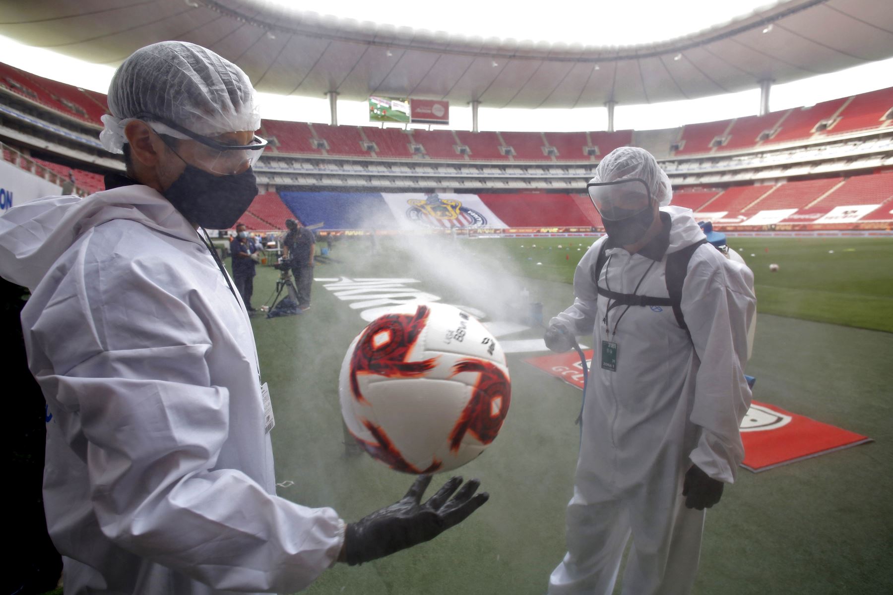 Trabajadores desinfectan balón de fútbol antes del comienzo del partido entre Guadalajara y León en el estadio Akron, en Guadalajara. Foto: AFP