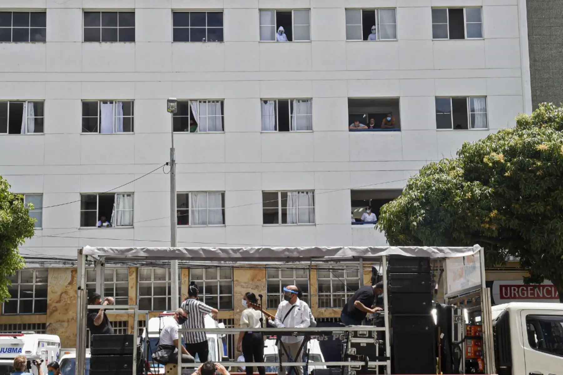 Trabajadores de la salud, pacientes y familiares miran desde las ventanas del hospital mientras una banda de música toca desde afuera en Medellín, Colombia. Foto: AFP