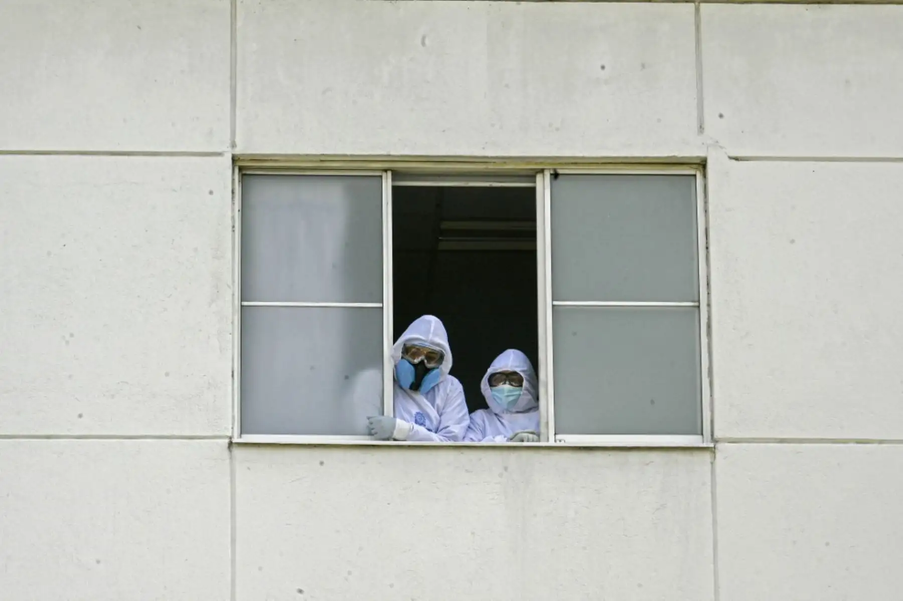 Trabajadores de la salud, pacientes y familiares miran desde las ventanas del hospital mientras una banda de música toca desde afuera en Medellín, Colombia. Foto: AFP