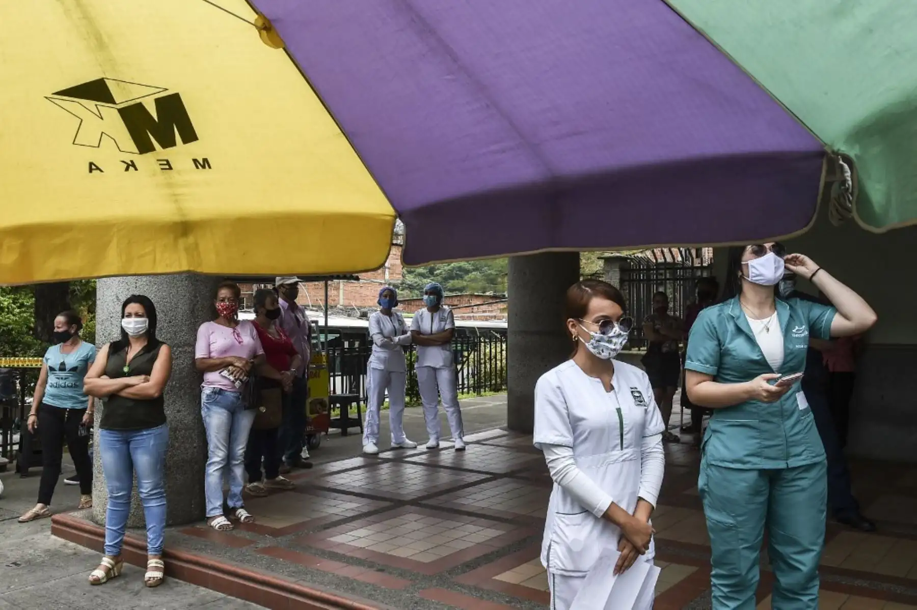 Trabajadores de la salud, pacientes y familiares miran desde las ventanas del hospital mientras una banda de música toca desde afuera en Medellín, Colombia. Foto: AFP