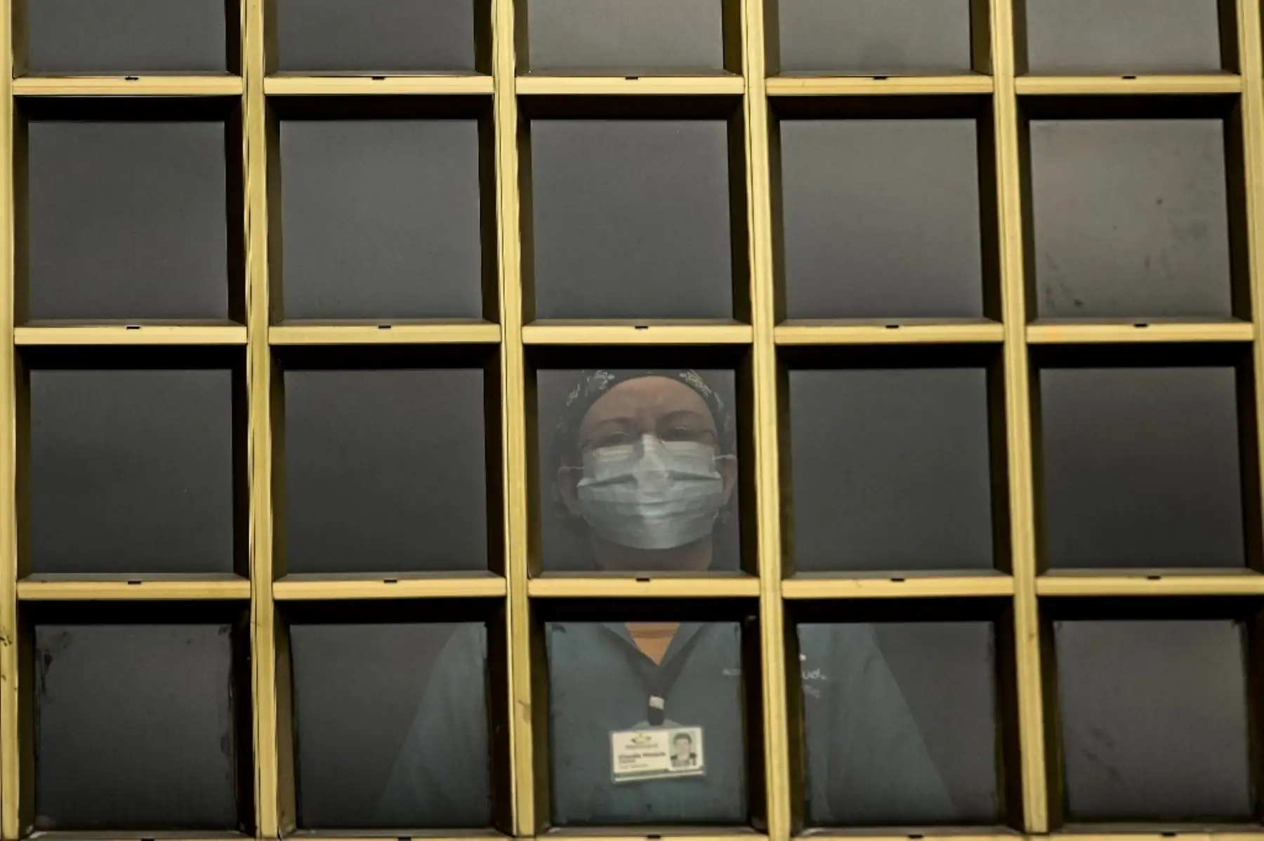 Trabajadores de la salud, pacientes y familiares miran desde las ventanas del hospital mientras una banda de música toca desde afuera en Medellín, Colombia. Foto: AFP