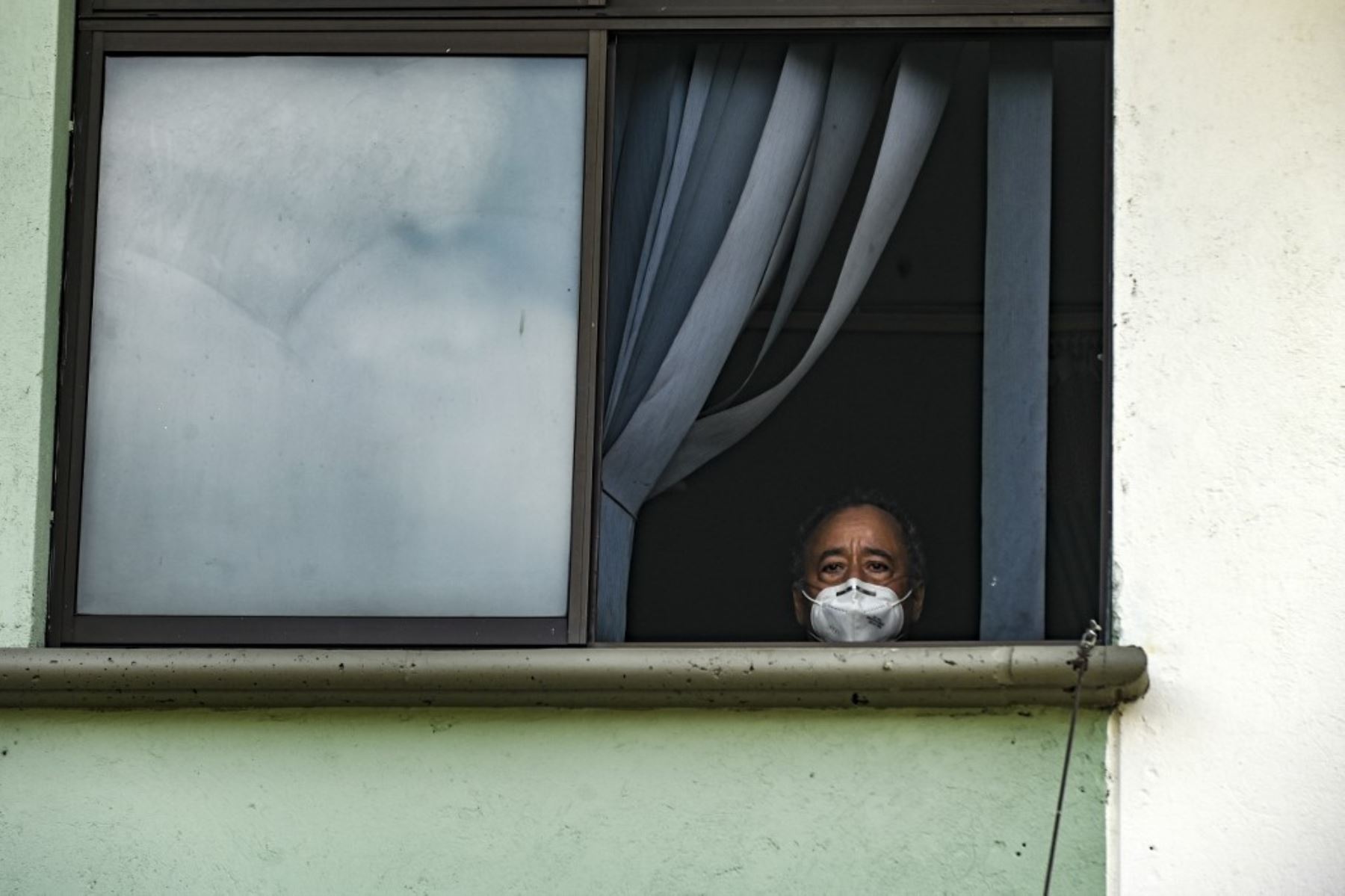 Trabajadores de la salud, pacientes y familiares miran desde las ventanas del hospital mientras una banda de música toca desde afuera en Medellín, Colombia. Foto: AFP
