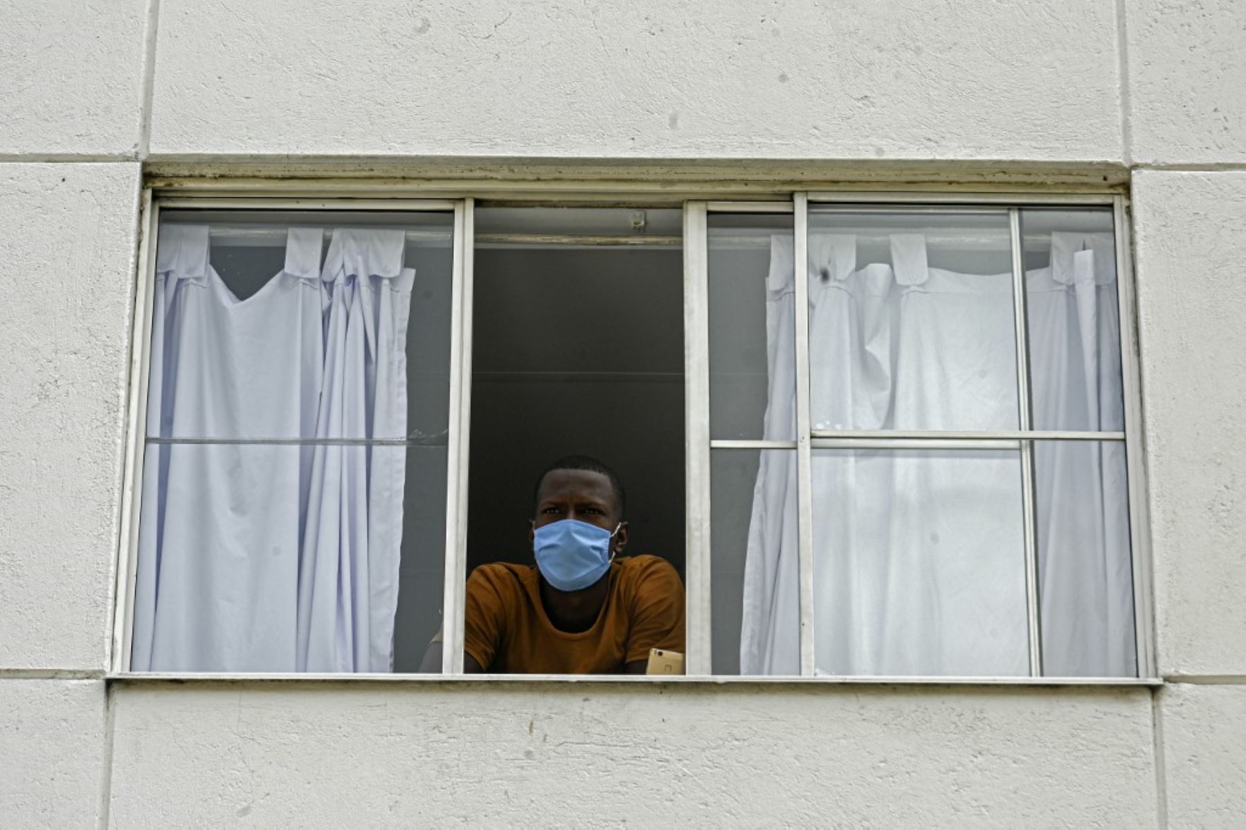 Trabajadores de la salud, pacientes y familiares miran desde las ventanas del hospital mientras una banda de música toca desde afuera en Medellín, Colombia. Foto: AFP