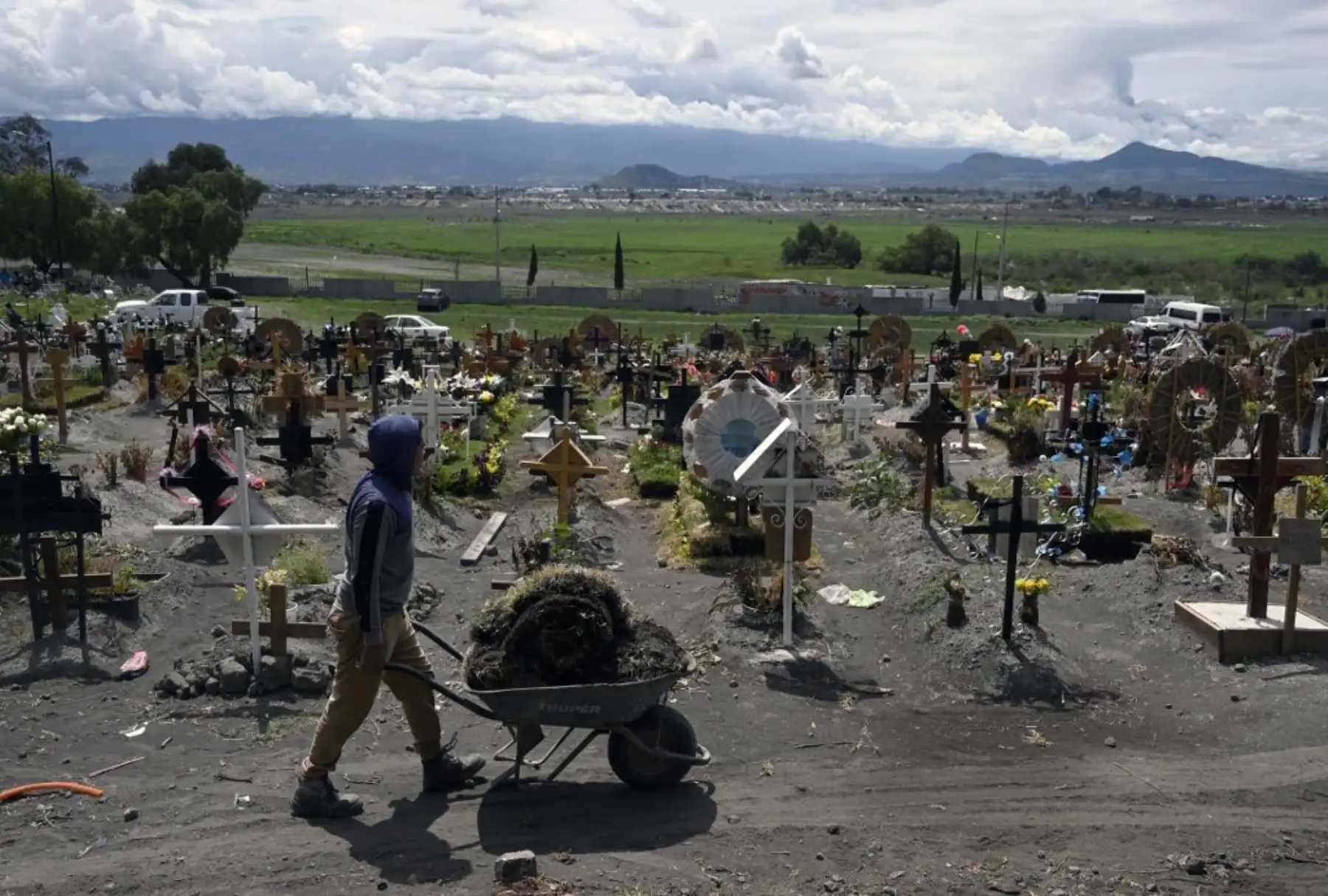 Familiares de víctimas asesinadas por covid-19 arreglan las tumbas en el área especial del Panteón Municipal del Valle de Chalco, Estado de México. Foto: AFP