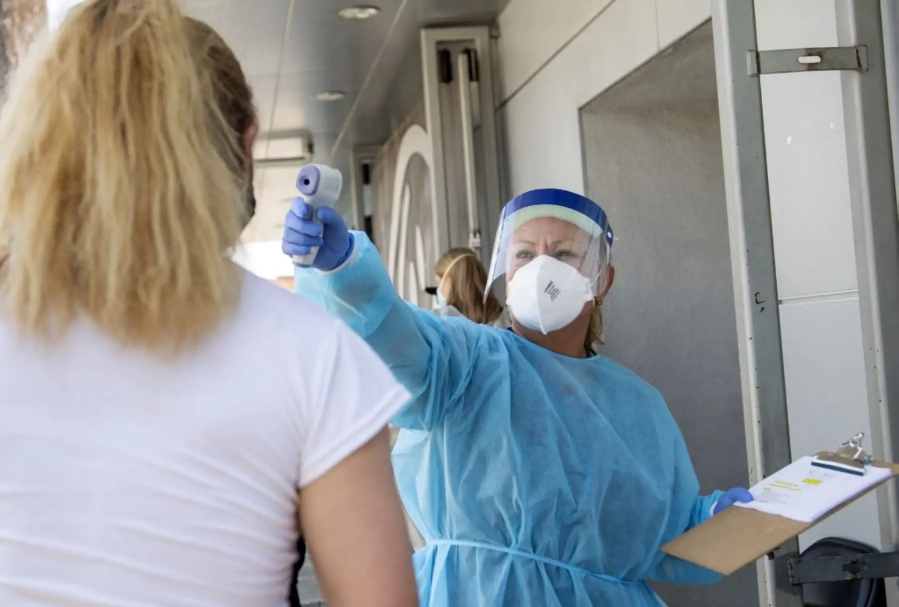Un trabajador de salud toma la temperatura de un paciente antes de enviarlo a una tienda de campaña para que lo examinen. Foto: AFP