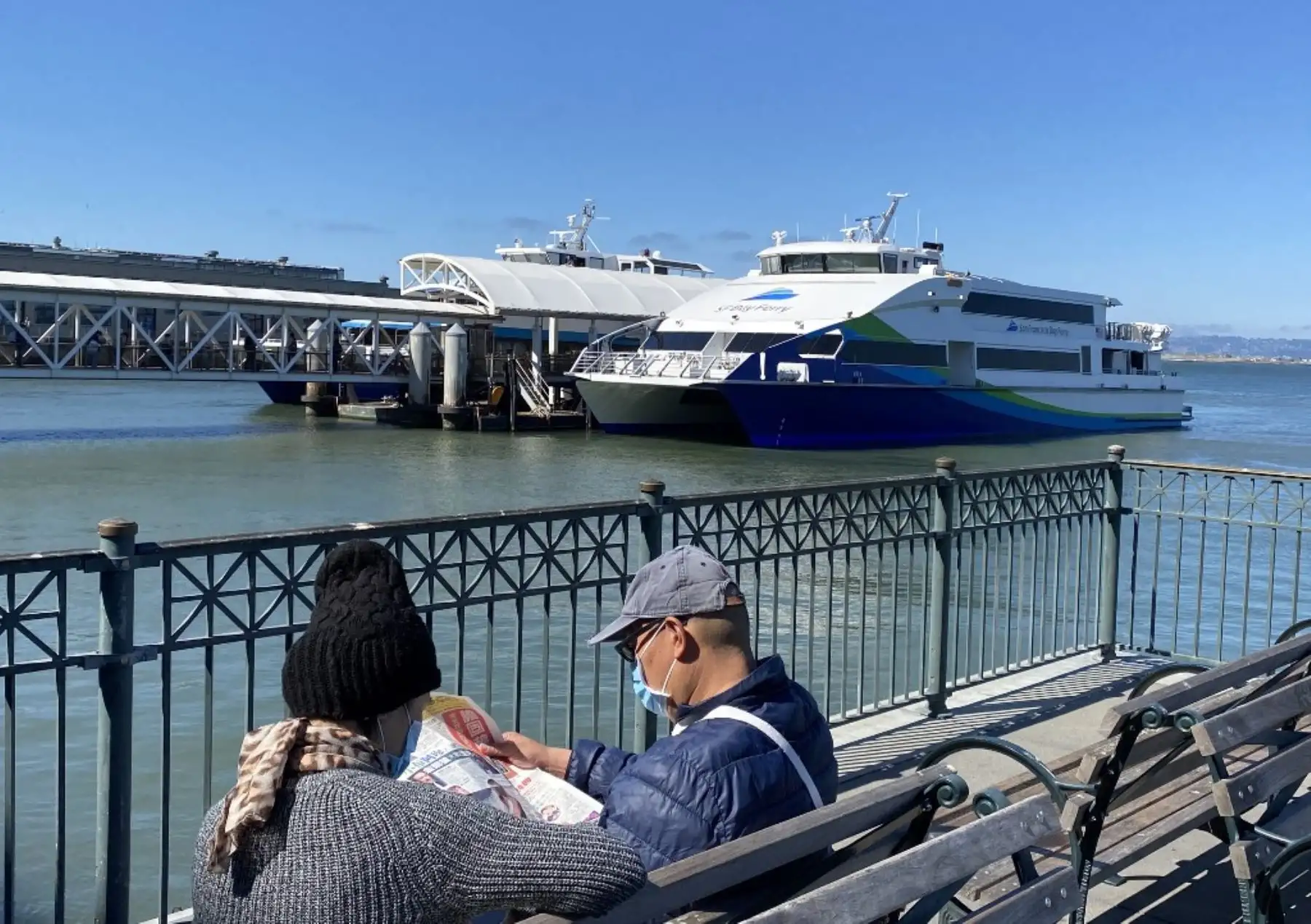 Personas con máscaras faciales lee las noticias en el muelle de San Francisco. Foto: AFP